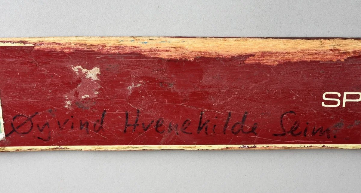 Close-up of a worn, scratched wooden surface with a handwritten inscription that reads 'Origin Hweihilde Stein'.