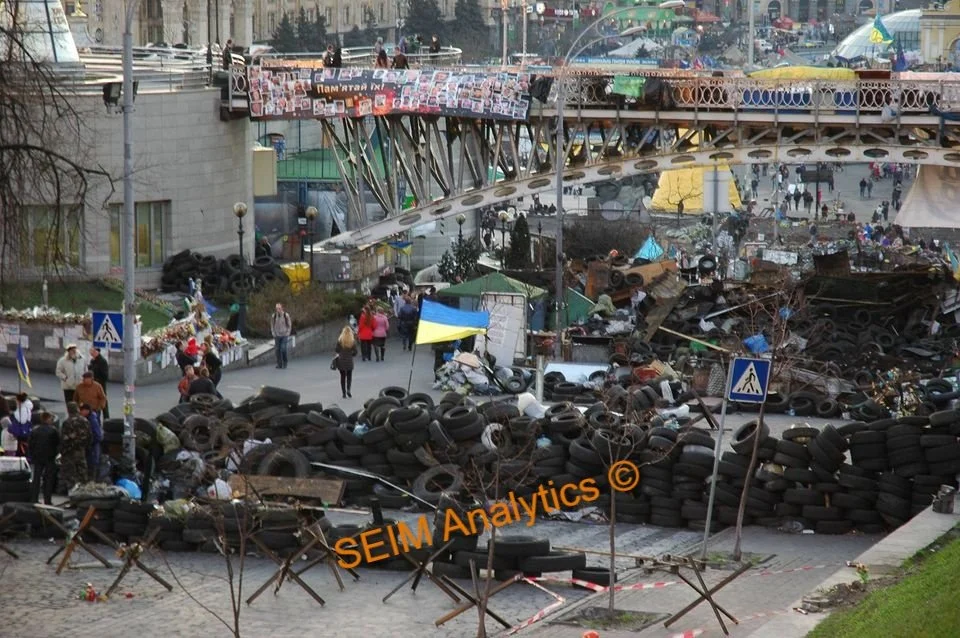 Euromaidan, or the Revolution of Dignity, March 2014, Kyiv. Streets blocked by piles of tires, debris, and wreckage with Ukrainian flags visible.