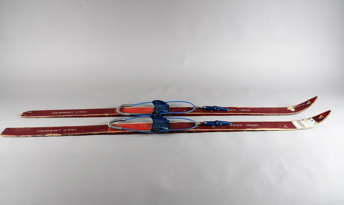 Pair of vintage ski boots with red and blue accents, labeled 'Full Laminated' and 'Speed Jump'.