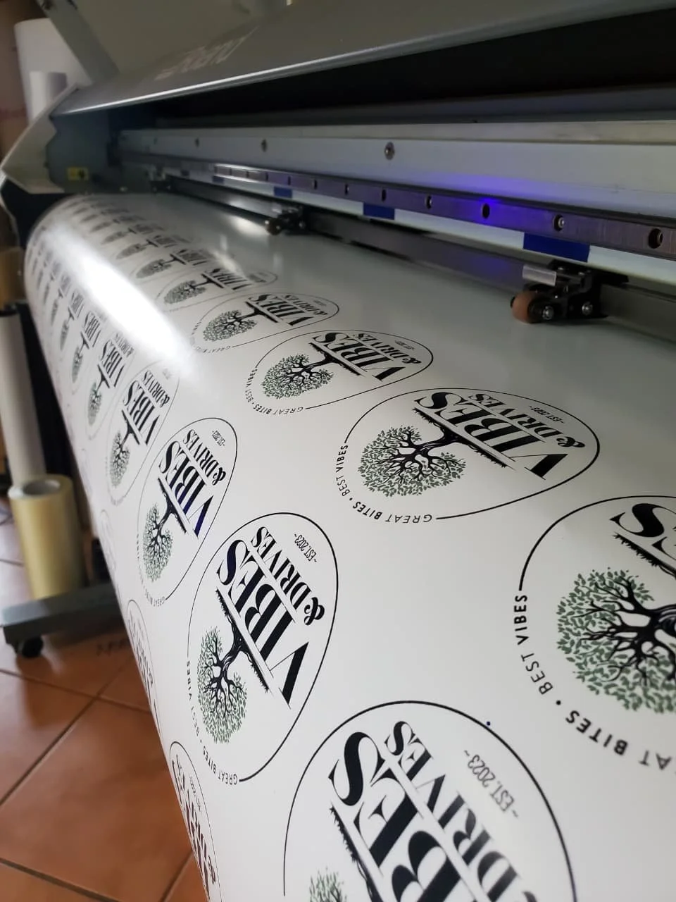 A large-format printer printing labels and vinyl stickers.