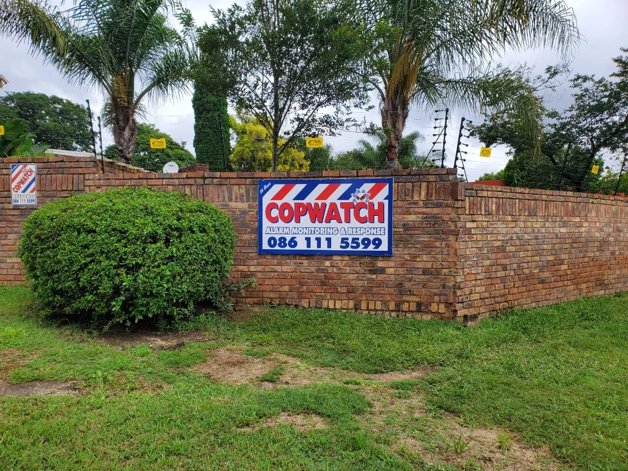 Sign on brick wall for Copwatch alarm monitoring and response, with a phone number 086 111 5599.