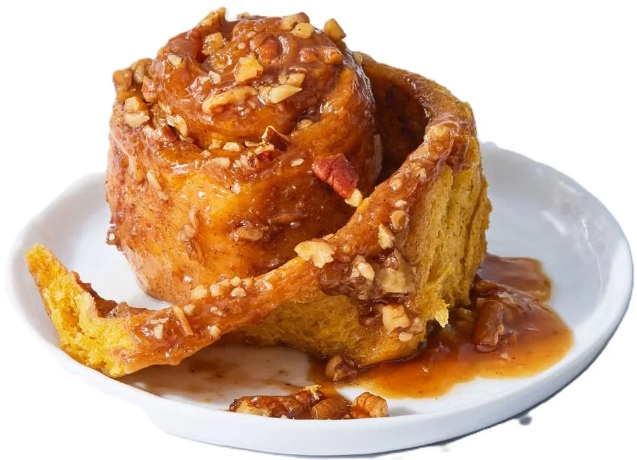 A close-up of a sticky bun sliced in half showing layers of pumpkin dough and cinnamon swirl Moist pumpkin sticky bun interior with visible cinnamon filling and fluffy texture.