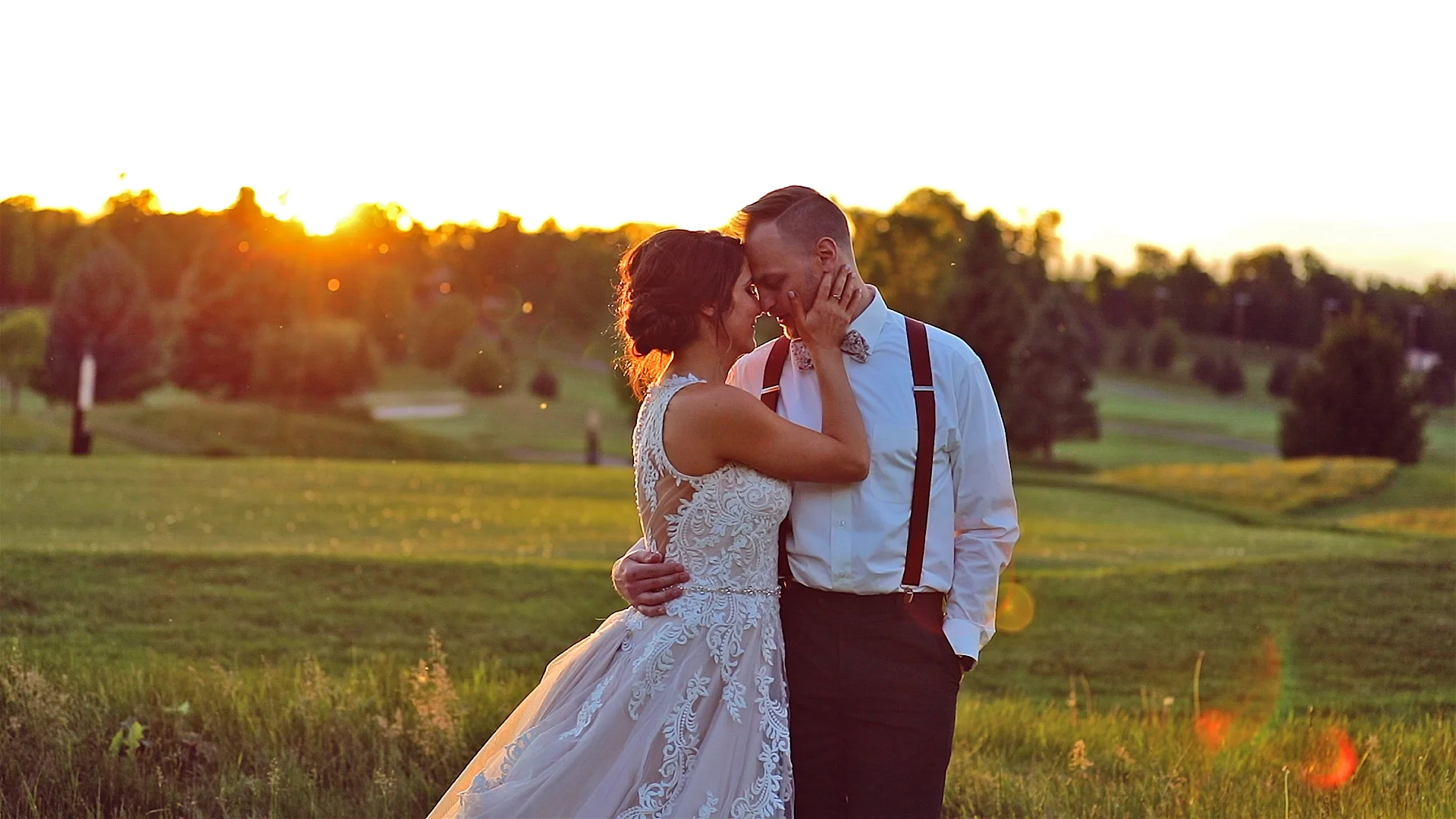 A bride and groom sharing a romantic moment on their wedding day in a lush green outdoor setting during sunset. Rochester NY Wedding videography