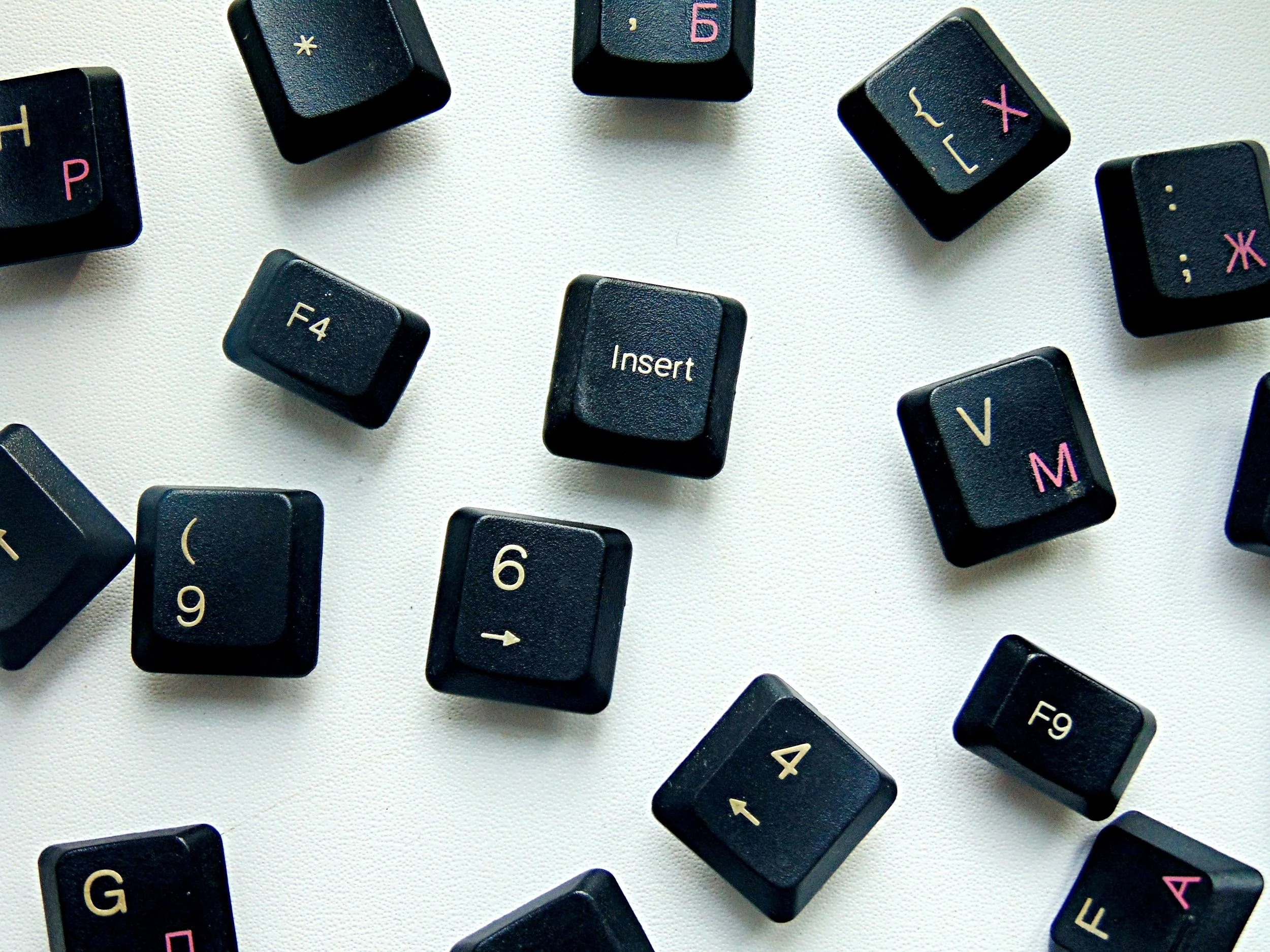 Scattered black keyboard keys with various symbols on a light background, including "Insert," "F4," and numeral keys.