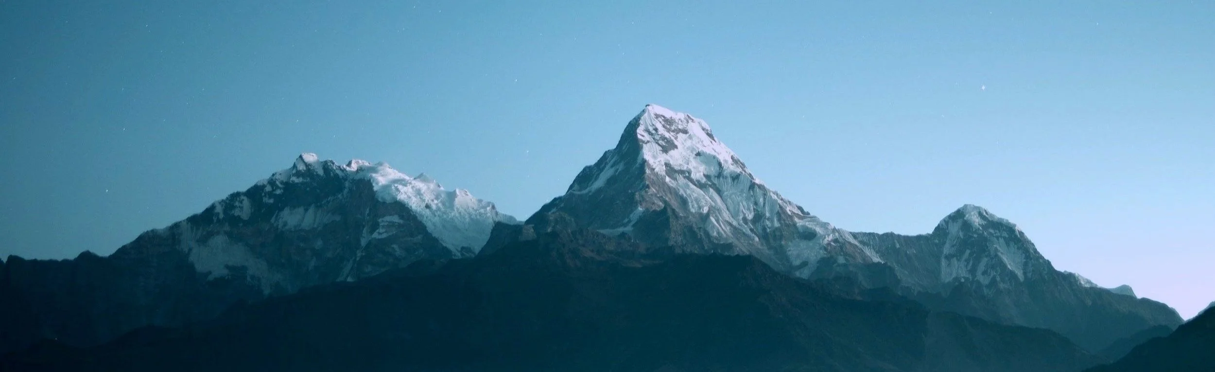 Mountain range with snow-capped peaks under a clear blue sky