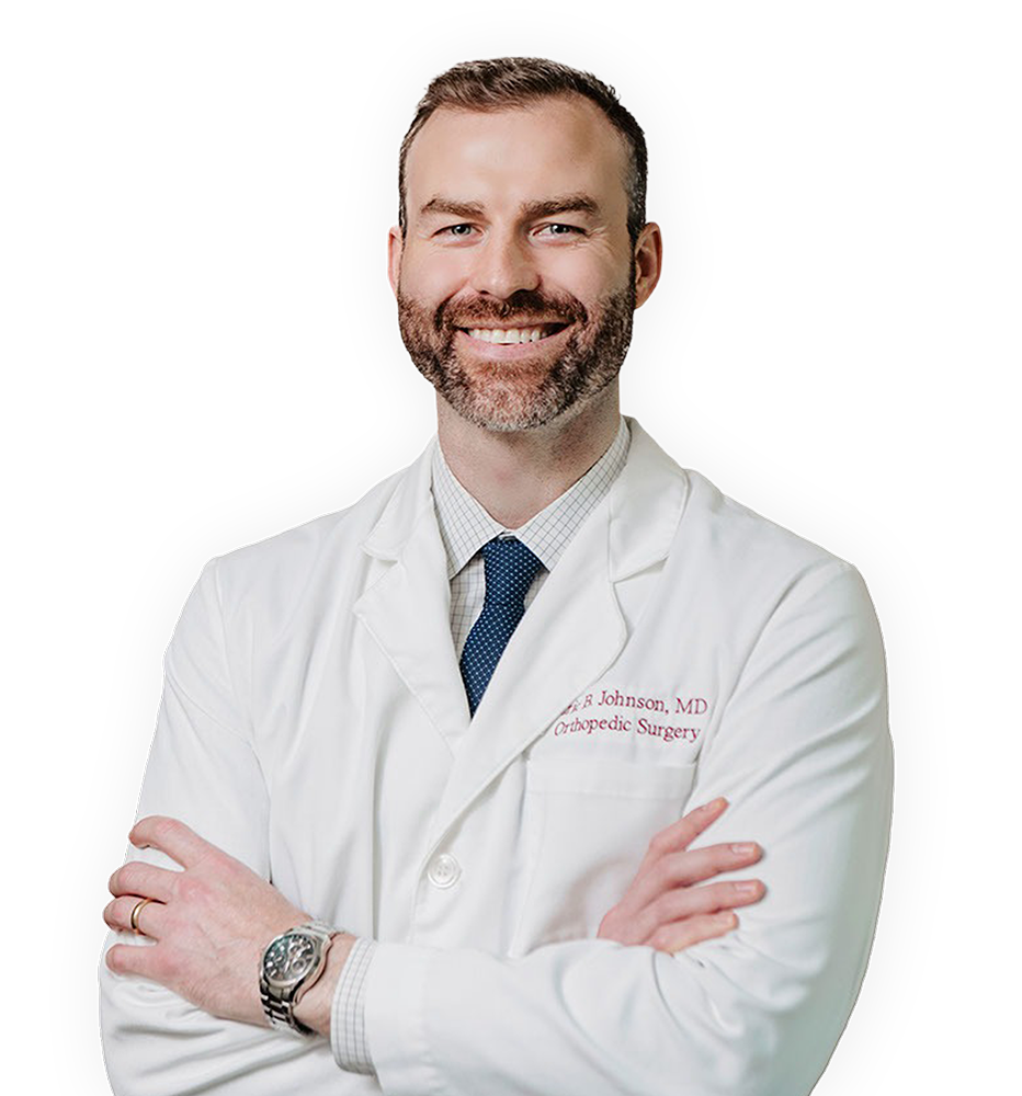A smiling man in a white doctor's coat with crossed arms, wearing a blue tie and a watch.