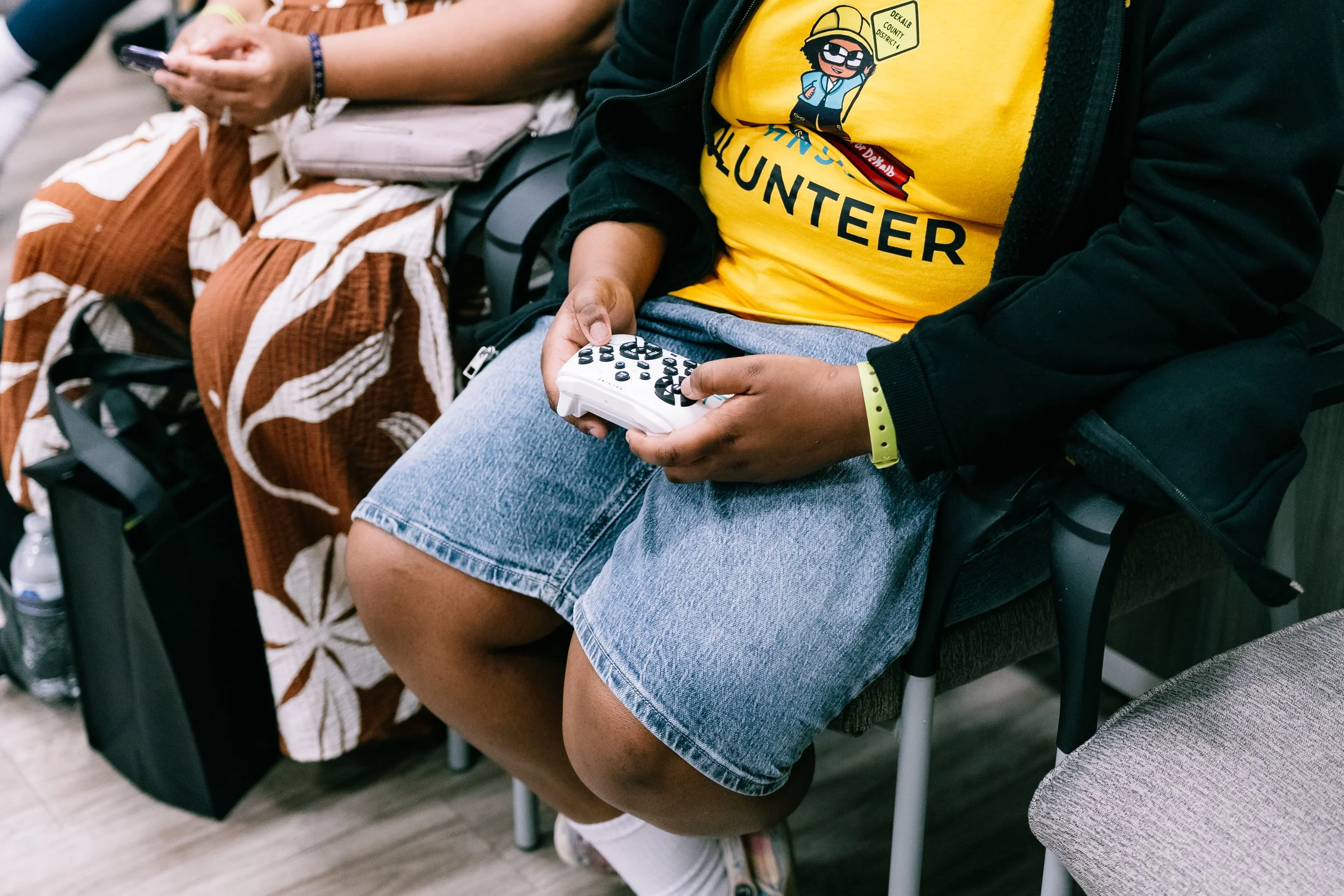 Close-up of a child seated and using a handheld remote control to operate one of the robotic dogs during Chakira’s Cookout.