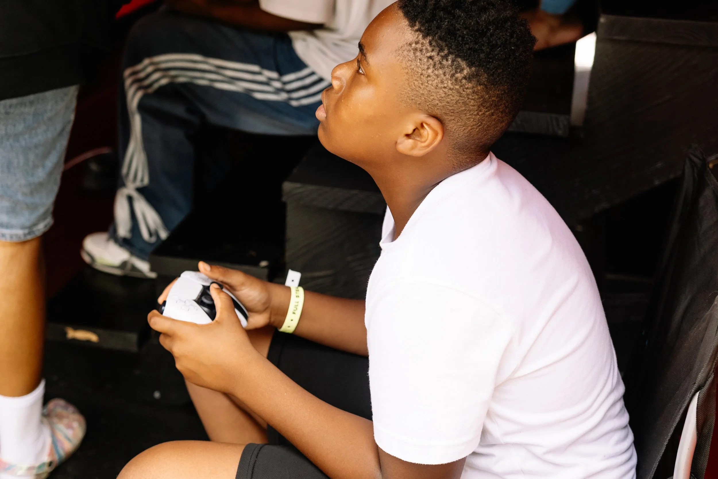 Young attendee holds a video game controller while playing inside the mobile gaming bus at Chakira’s Cookout.