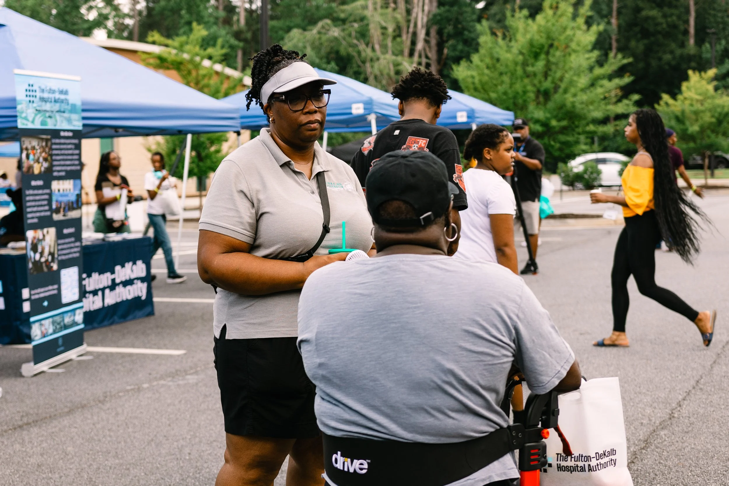 Commissioner Chakira Johnson speaks with an attendee using a mobility scooter as other guests mingle nearby at Chakira’s Cookout.