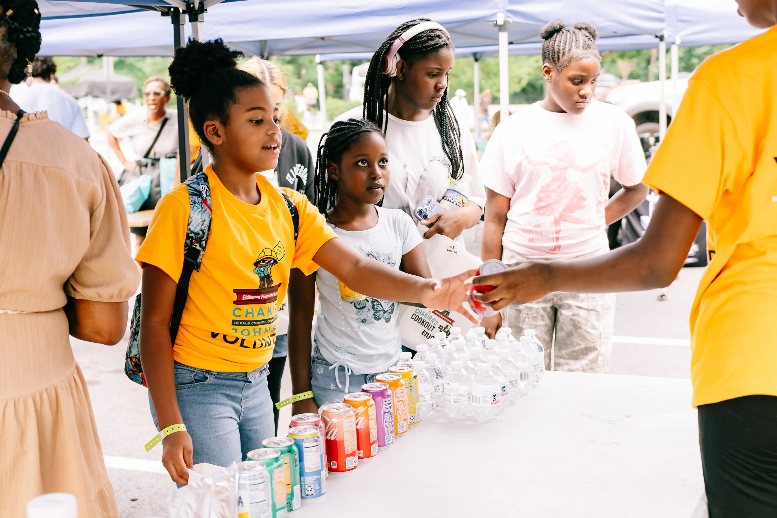 Event attendees receive food and drinks from volunteers at an outdoor refreshment station during Chakira’s Cookout.