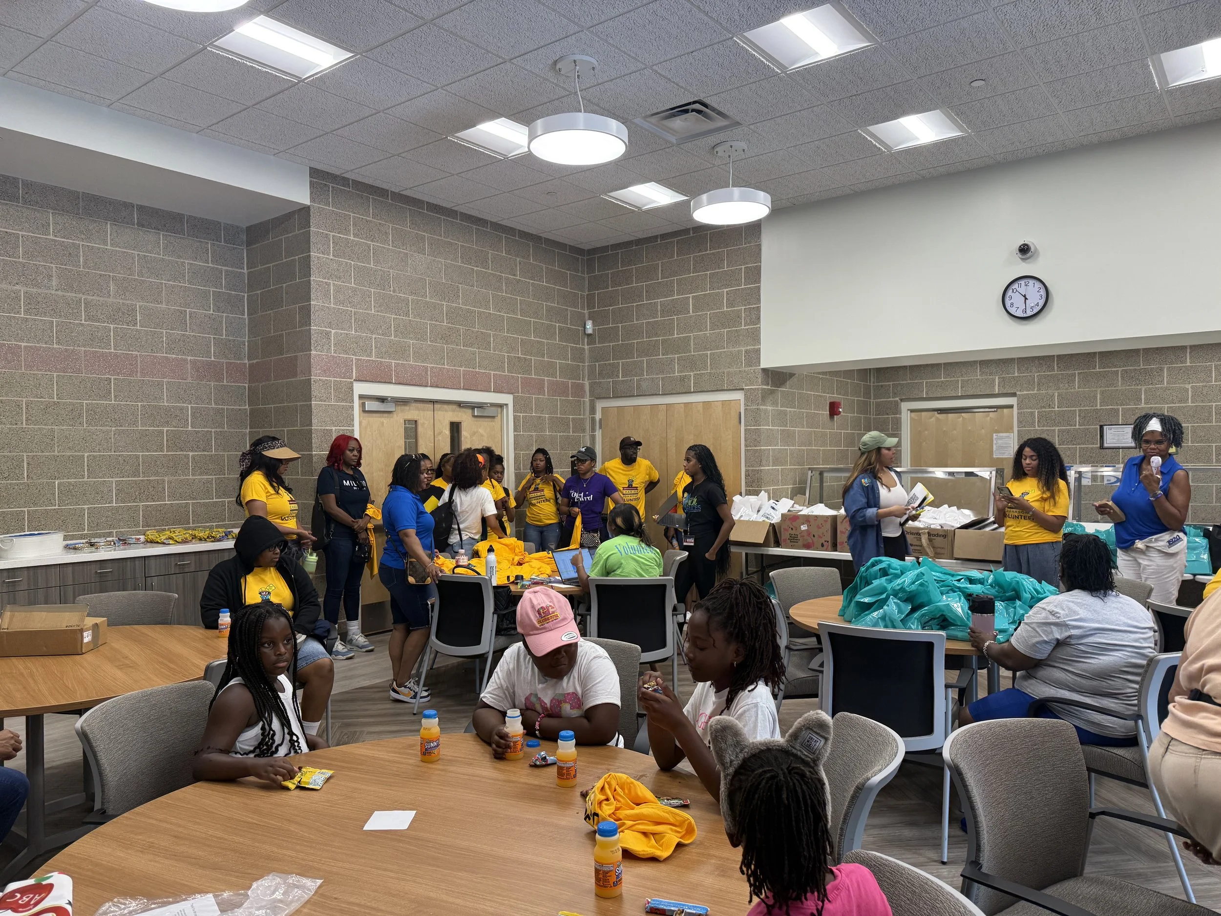 Volunteers gather in the event control room, surrounded by boxes, teal event branded bags and stacks of yellow event Volunteer shirts as they organize supplies before Chakira’s Cookout.
