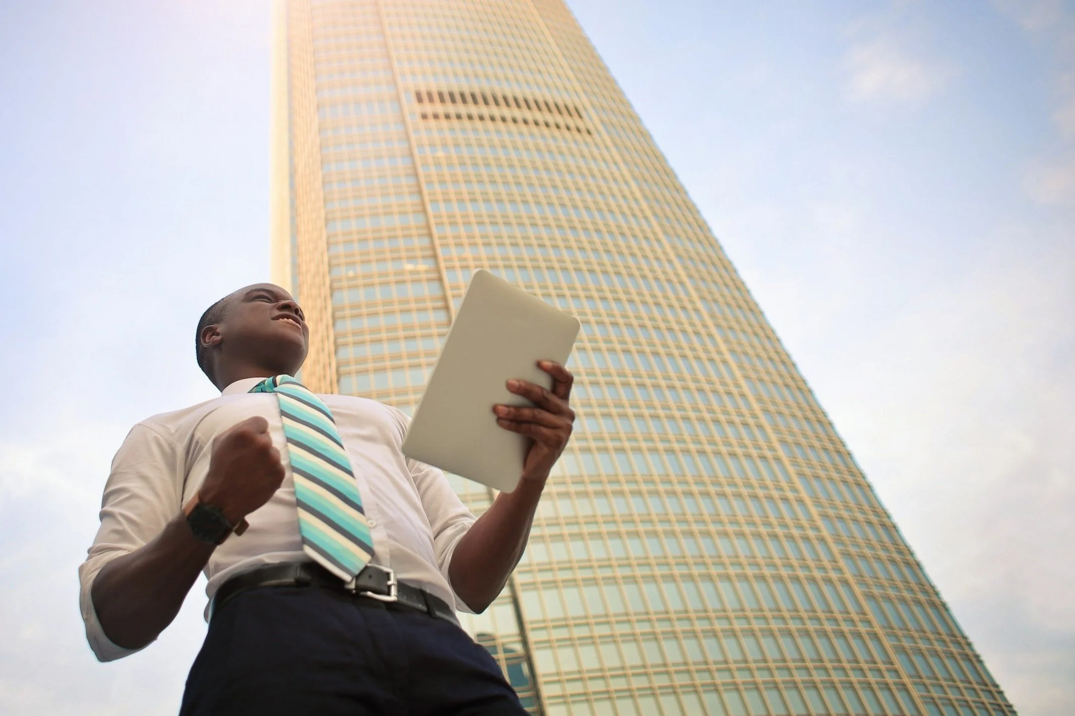 A professional grins and fistpumps as he stands in front of a city building.