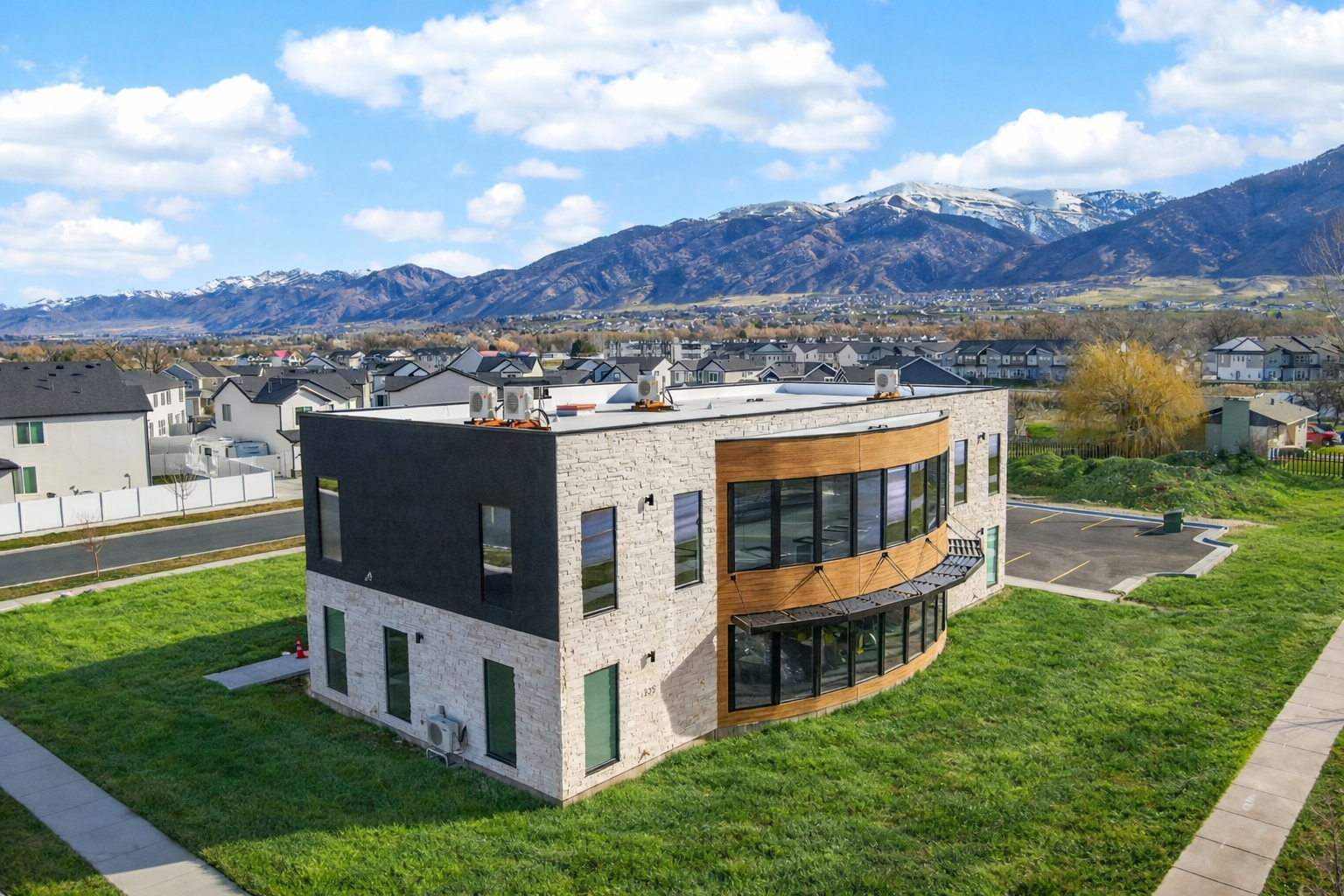 Modern two-story orthodontic office, white brick and black exterior, surrounded by green lawn in a suburban neighborhood with mountains in the background.