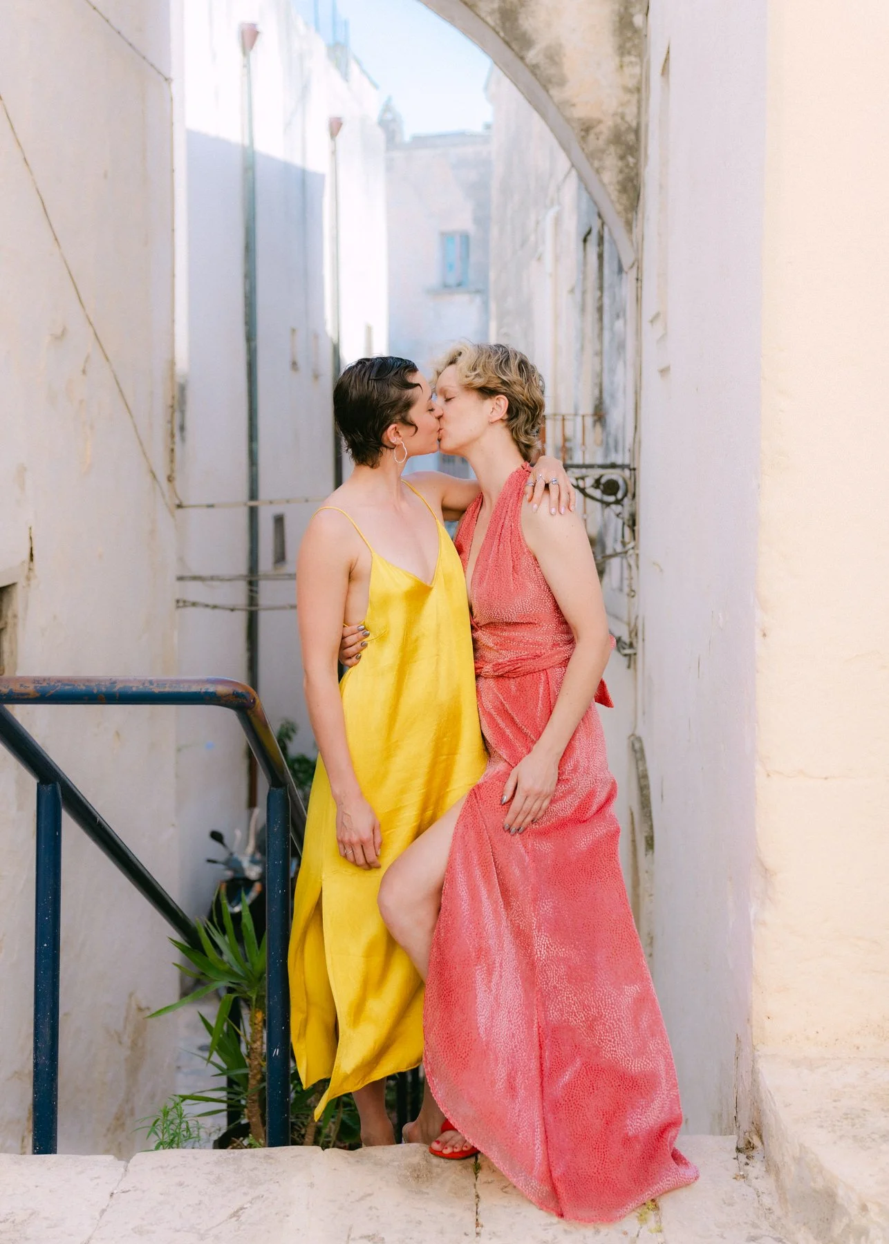 Two women in colorful dresses kissing.