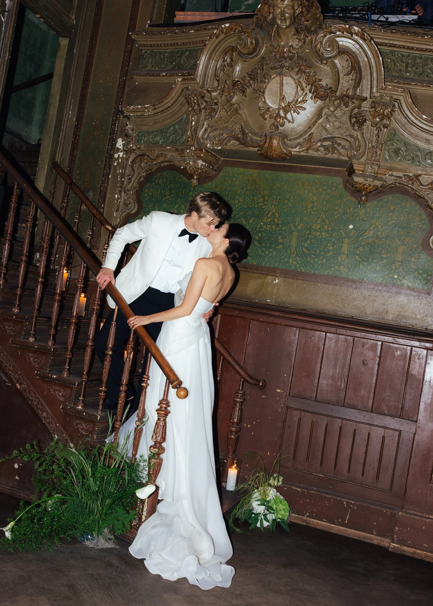 Bride and groom in elegant clothes kissing on a historic staircase at Clärchens Ballhaus, Berlin