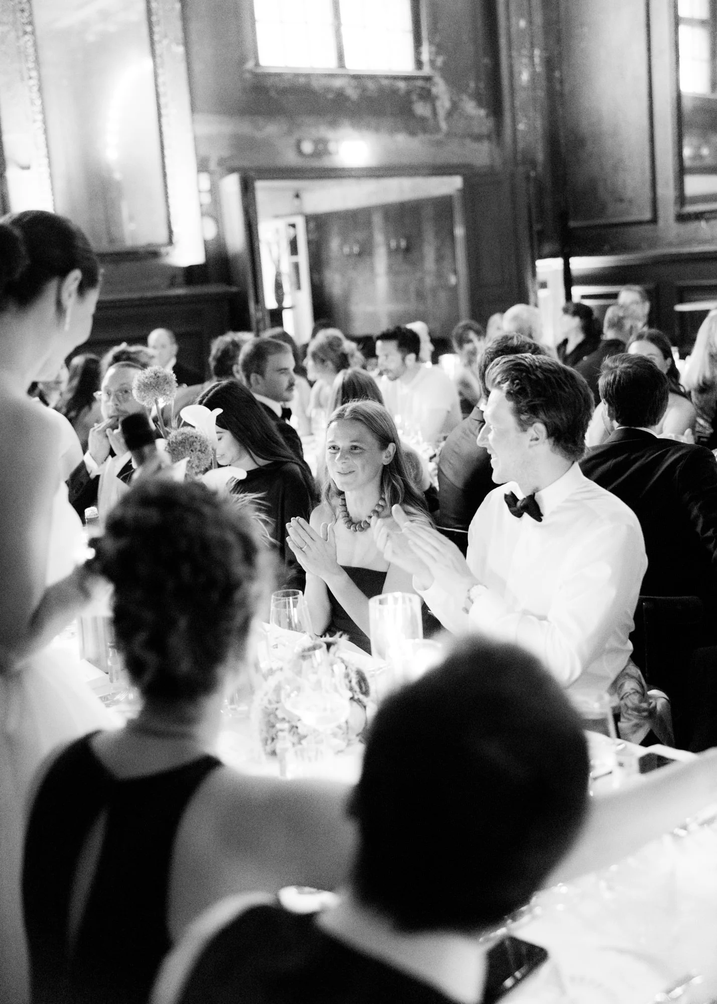 Black and wihte image of cheering guests at a speech of the bride at Clärchens Ballhaus Berlin