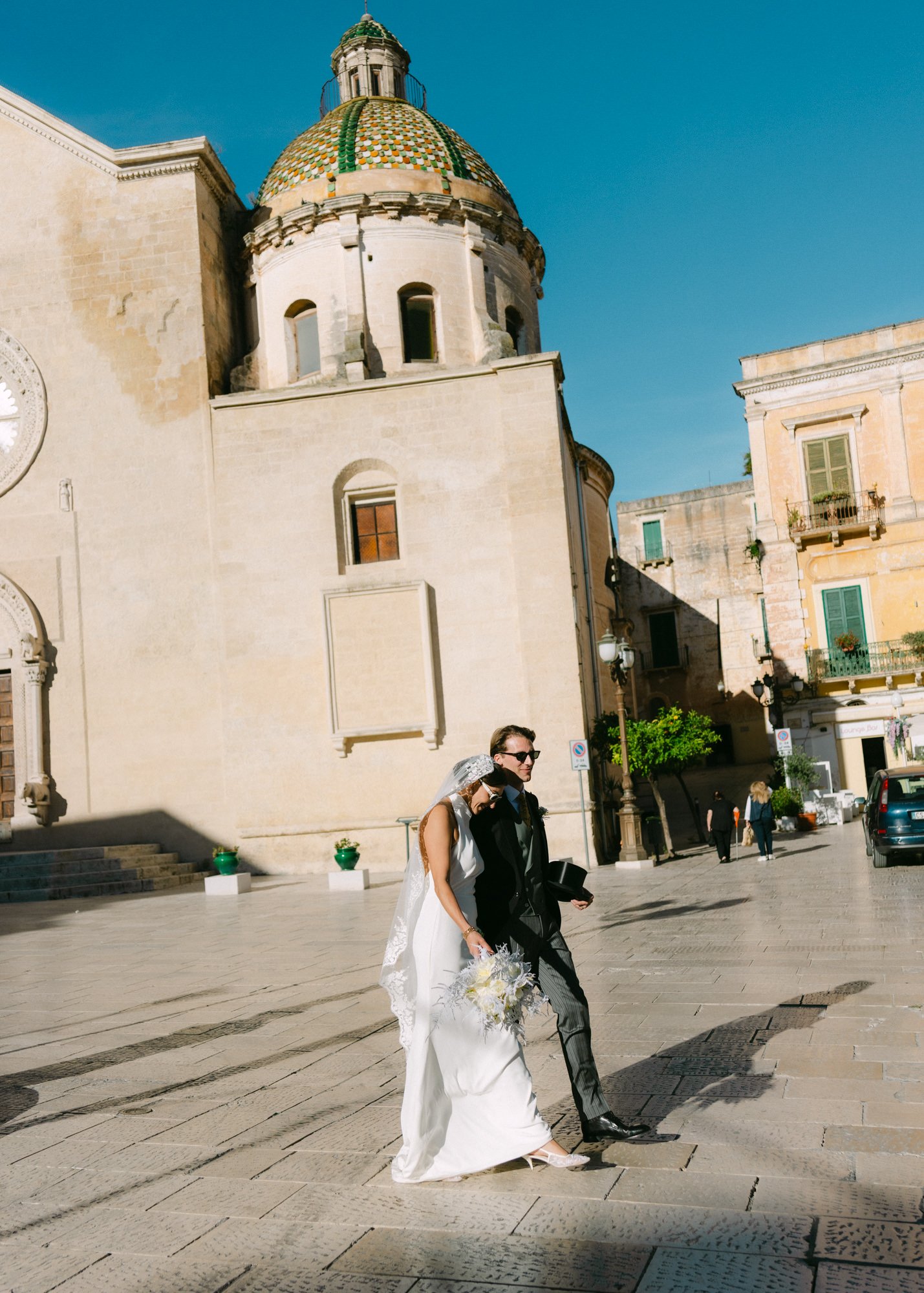 Newly weds walking together in front of a church in Puglia, Italy