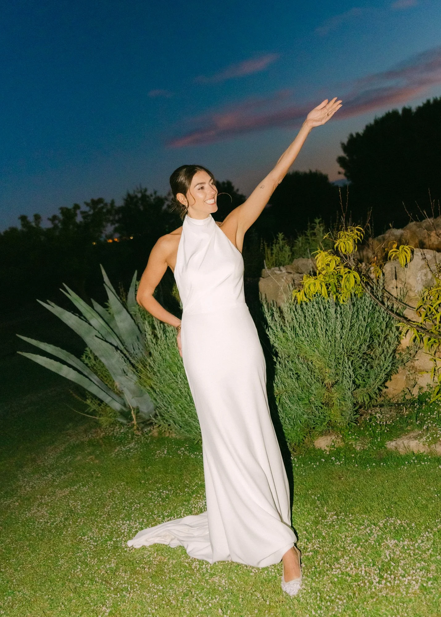 Bride in an elegant and modern dress against a colorful night scene in italy