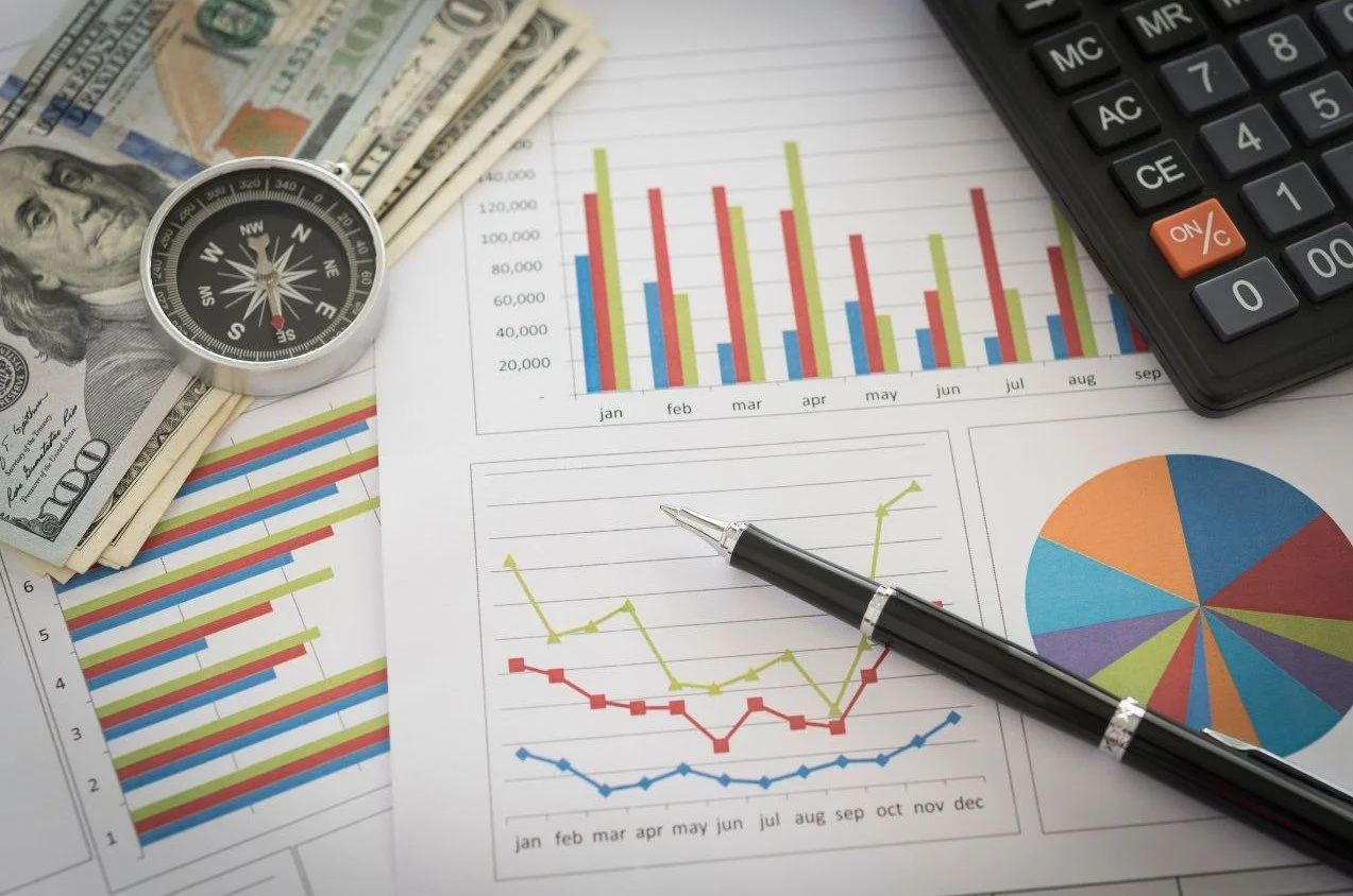Compass-Money-Pen-and-Calculator-Rest-On-Papers-with-Charts.jpg