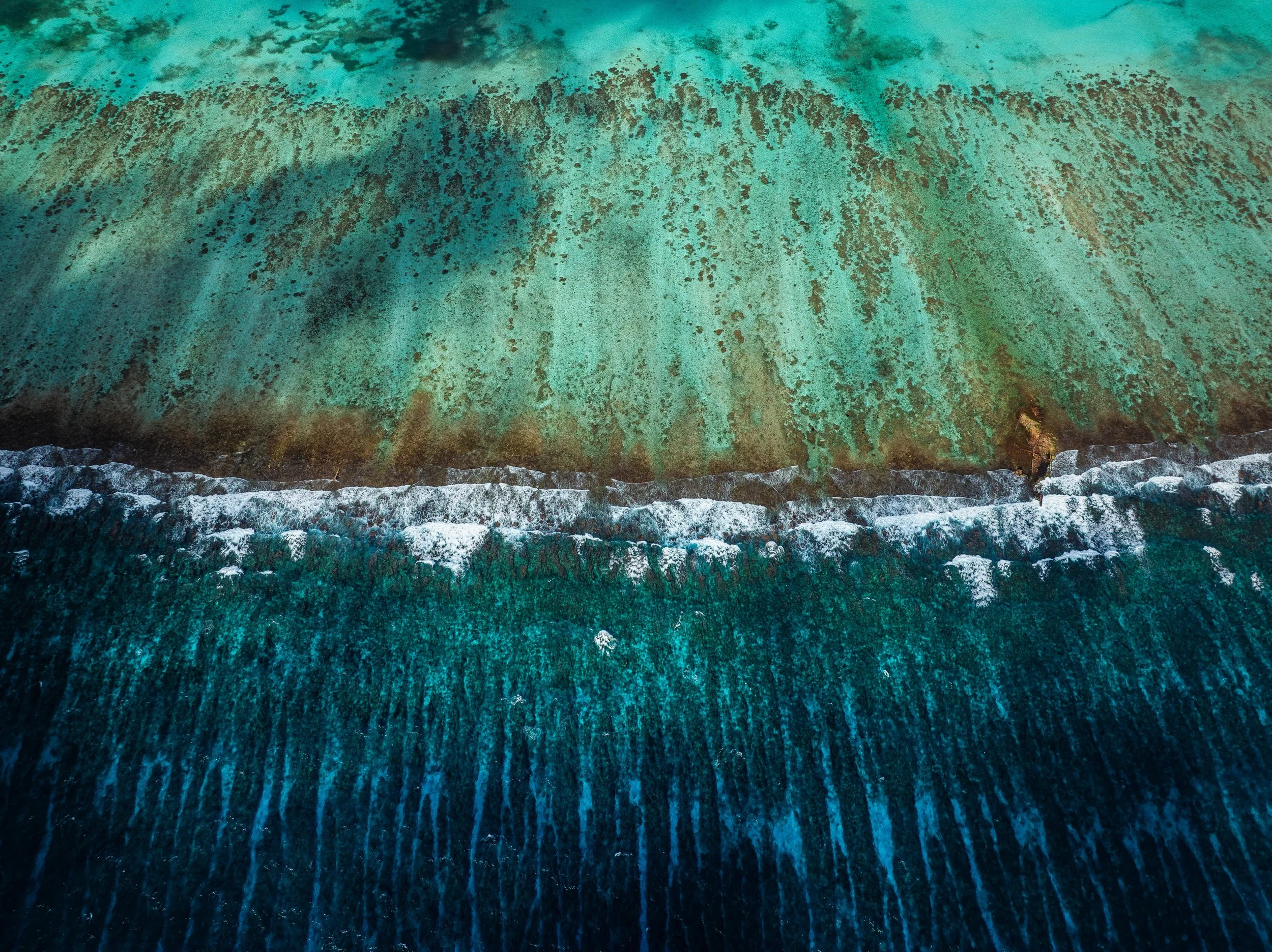 Aerial view of a of sea/reef with turquoise and dark blue waters in Belize.