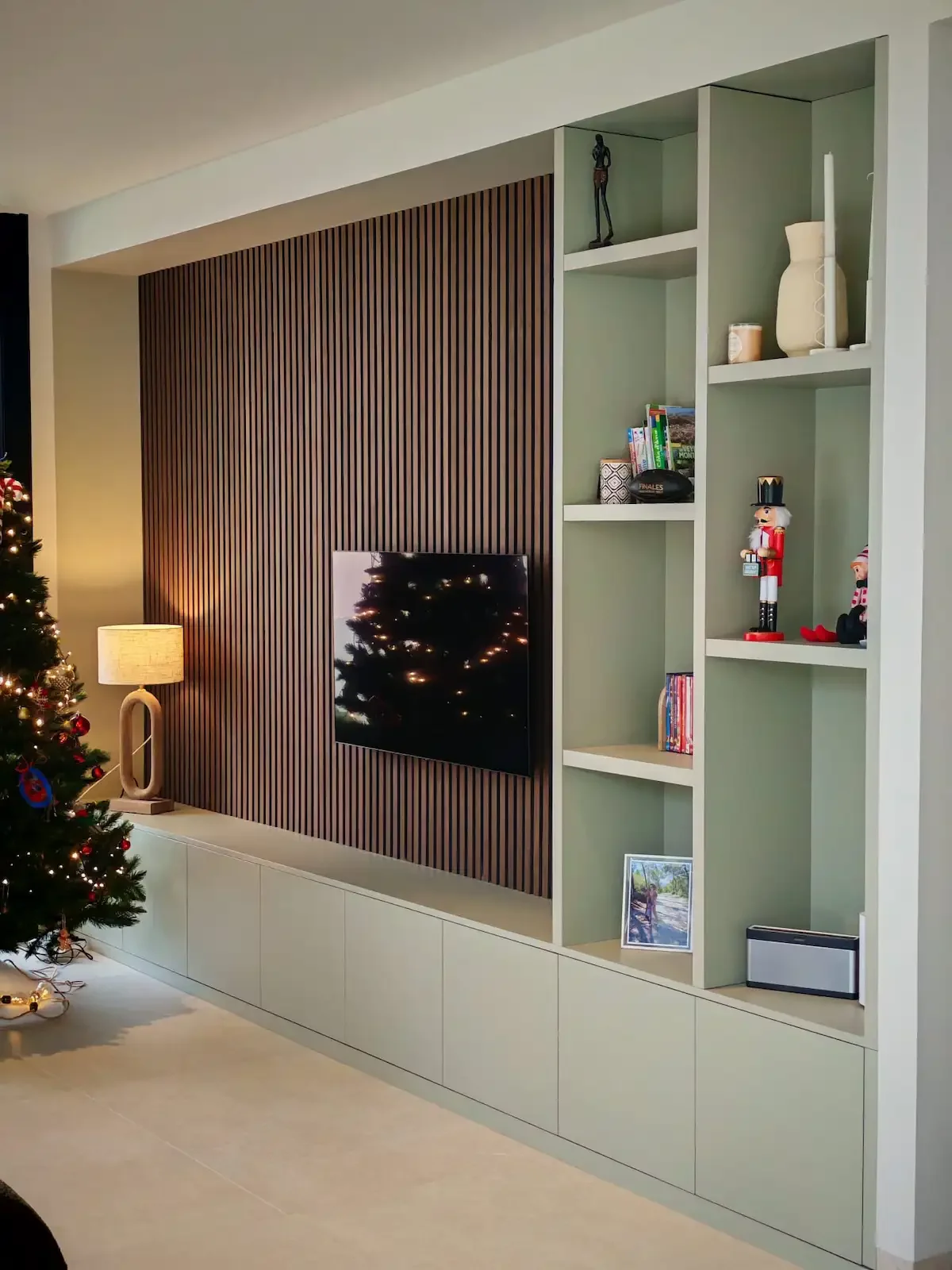 Agencement sur mesure avec meuble TV intégré, bibliothèque et panneau bois à lames verticales dans un salon contemporain à Clermont-Ferrand.