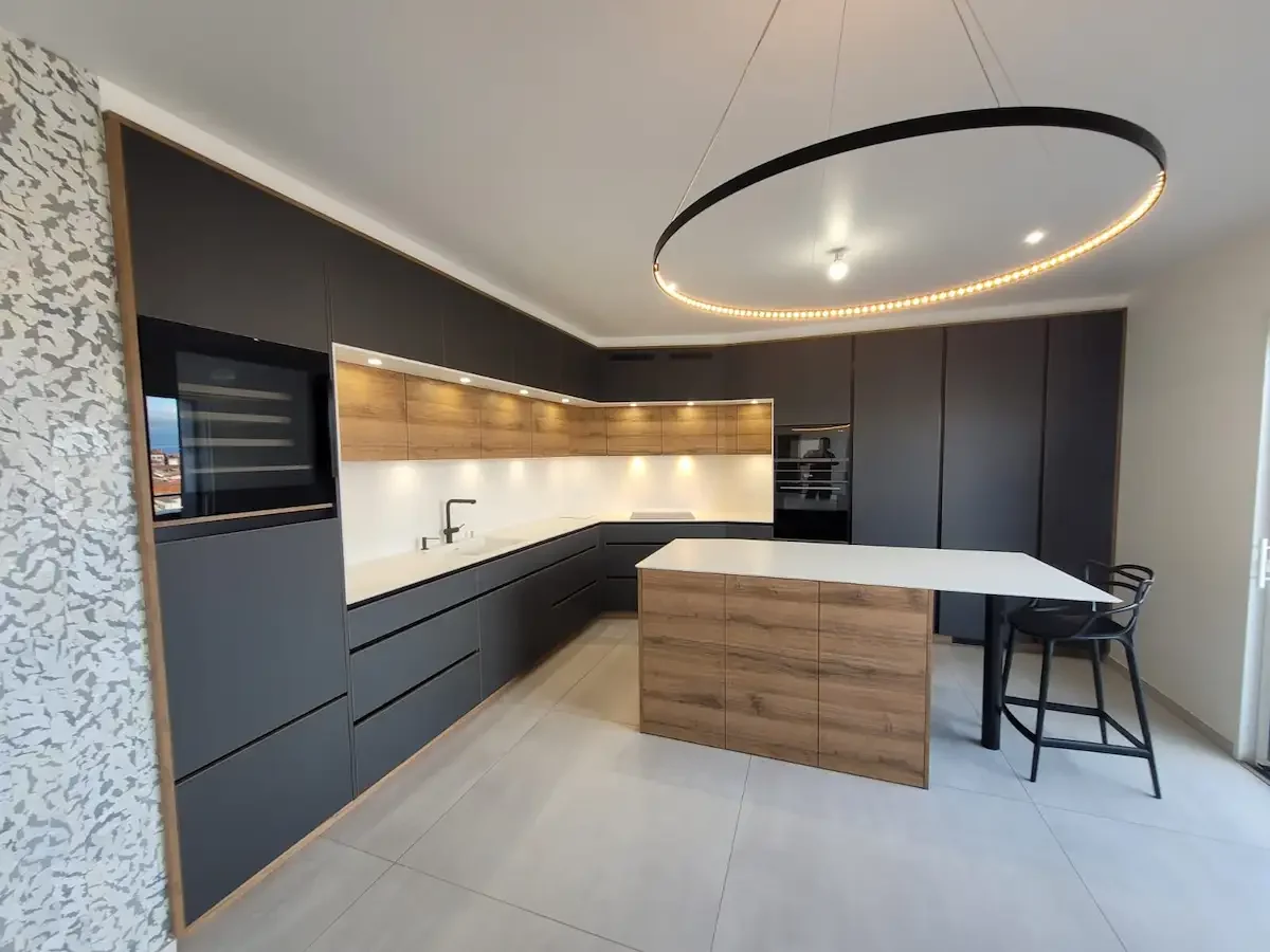 Cuisine sur mesure contemporaine avec îlot central, façades noir mat et bois, éclairage intégré et électroménager encastré, réalisée à Clermont-Ferrand.