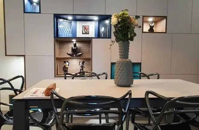 Cuisine sur mesure avec espace repas intégré, table contemporaine, niches décoratives éclairées et rangements sur mesure, réalisée à Clermont-Ferrand.