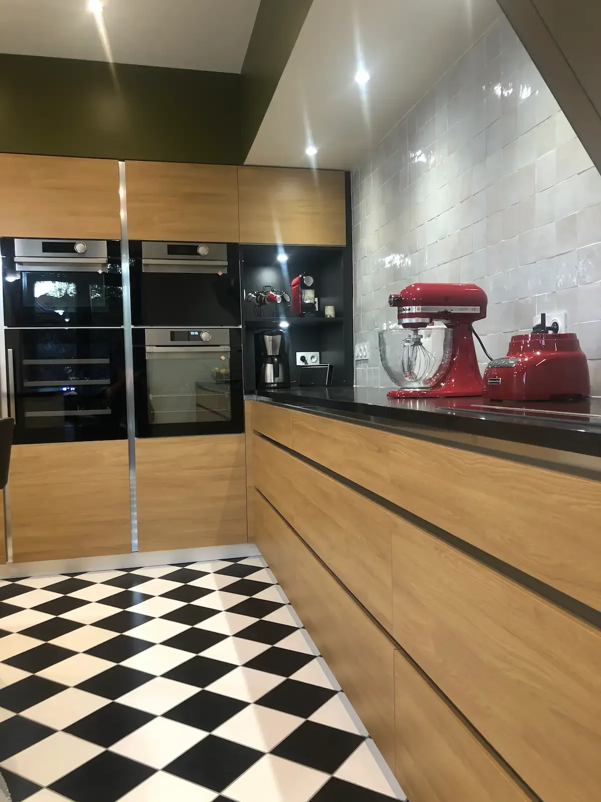 Cuisine contemporaine en bois et noir avec carrelage damier et crédence en zellige, conçue sur mesure par Oleksiak à Clermont-Ferrand.