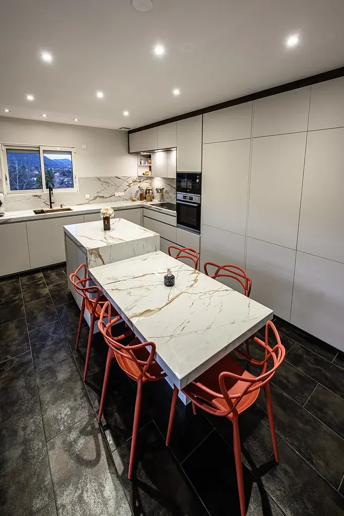 Cuisine sur mesure moderne avec îlot central en pierre, rangements toute hauteur et électroménager intégré, réalisée à Clermont-Ferrand.