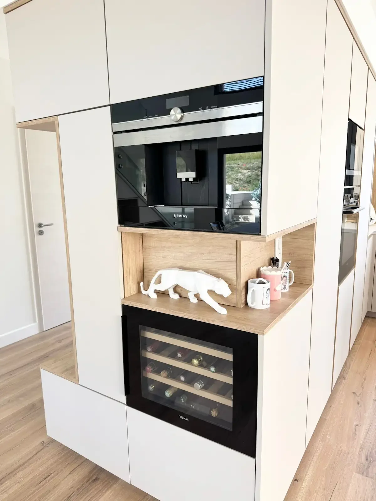 Cuisine contemporaine blanche et bois avec colonne intégrée abritant four, machine à café et cave à vin, réalisée sur mesure par Oleksiak à Clermont-Ferrand.