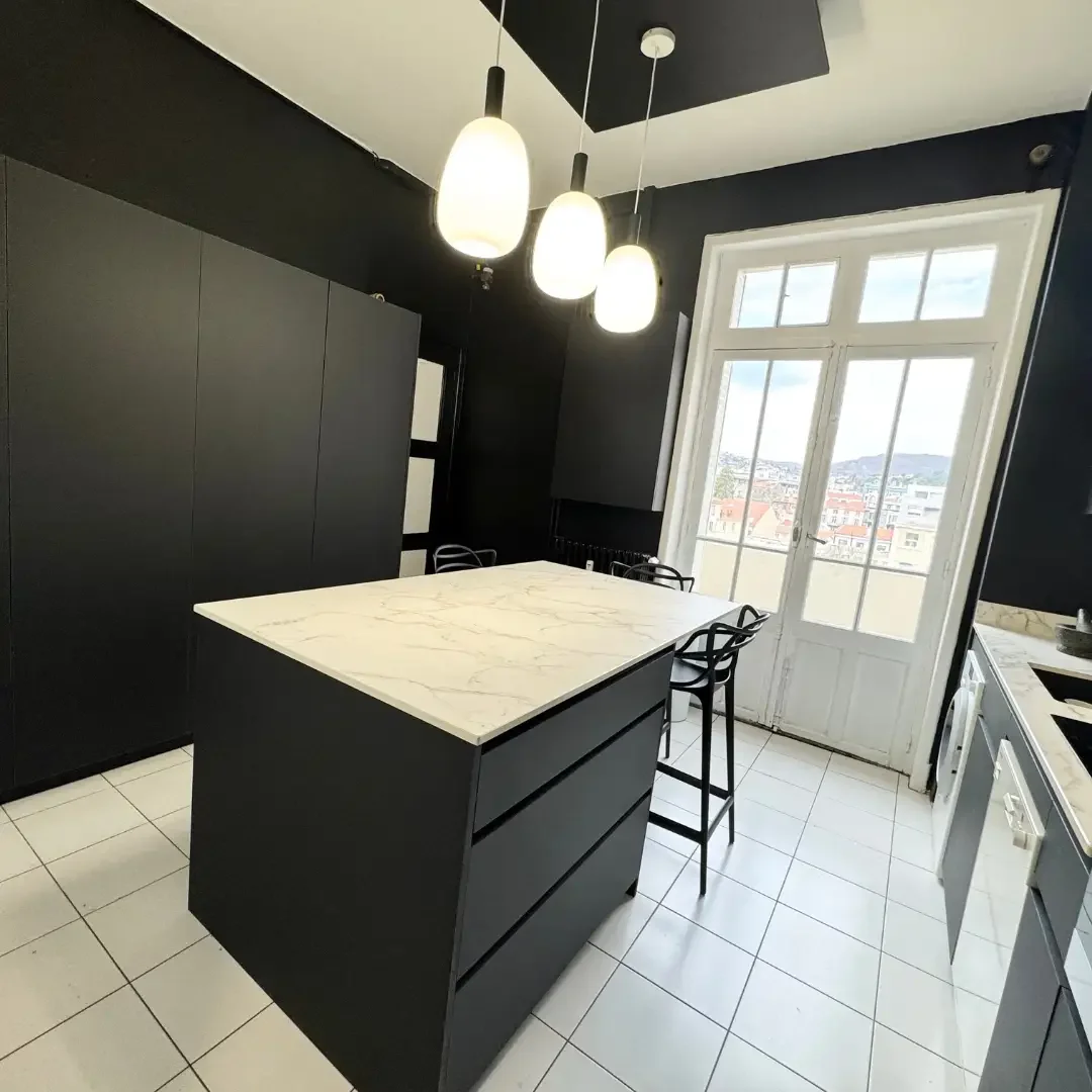 Cuisine noire mate avec îlot central et plan de travail effet marbre, réalisée sur mesure par Oleksiak à Clermont-Ferrand.