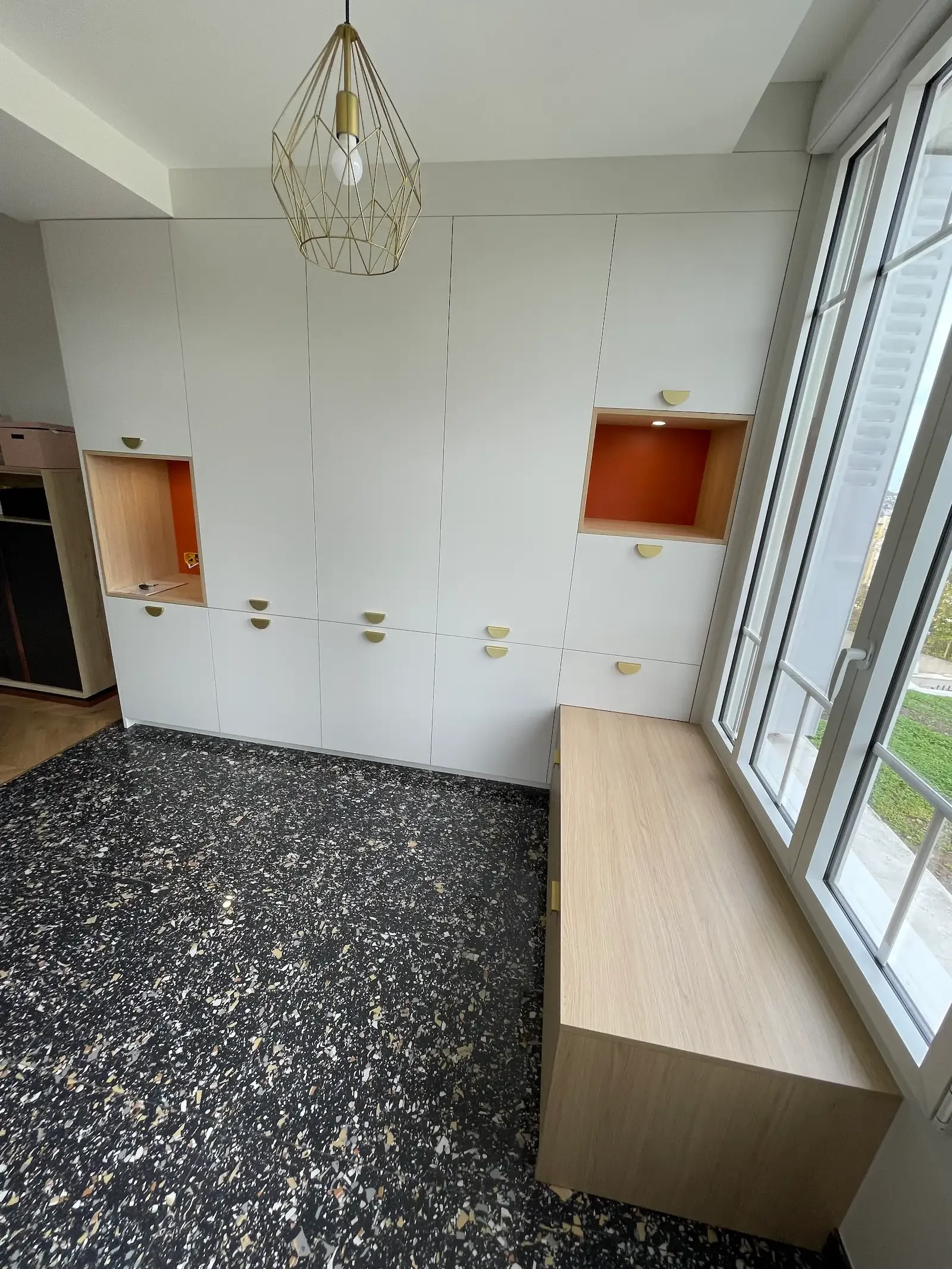 Dressing sur mesure blanc et bois avec niches colorées et poignées laiton, conçu par Oleksiak à Clermont-Ferrand. Un agencement lumineux et plein de caractère.