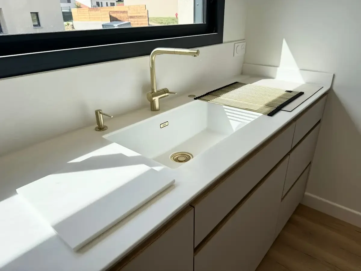 Cuisine cachemire avec plan de travail LG et évier intégré minimaliste et robinetterie en laiton brossé, réalisée sur mesure par Oleksiak à Clermont-Ferrand.