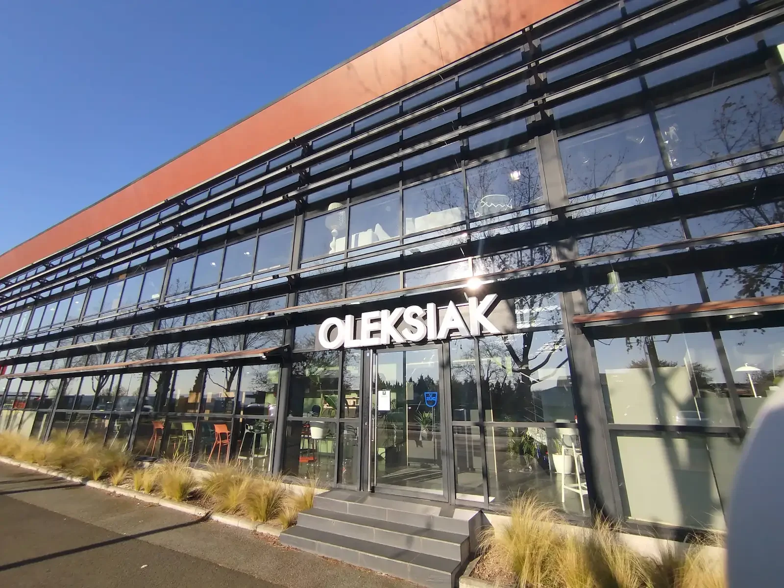 Façade du showroom Oleksiak à Clermont-Ferrand, espace dédié à la conception et à la fabrication de cuisines, dressings et aménagements sur mesure, situé dans un bâtiment moderne et lumineux.