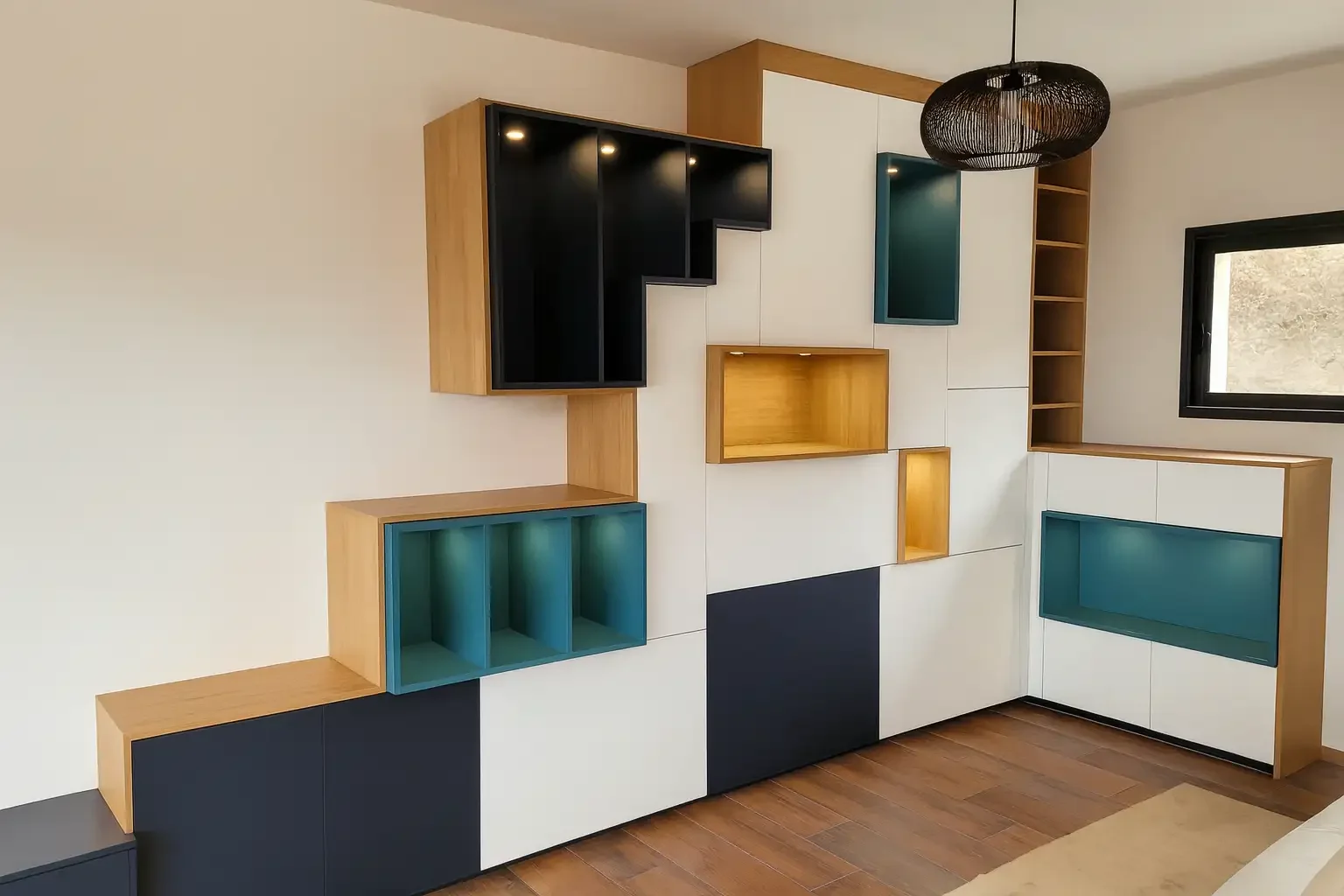 Meuble sur mesure design réalisé par Oleksiak à Clermont-Ferrand, associant bois clair, blanc, bleu canard et noir pour une composition graphique et contemporaine dans un salon moderne.
