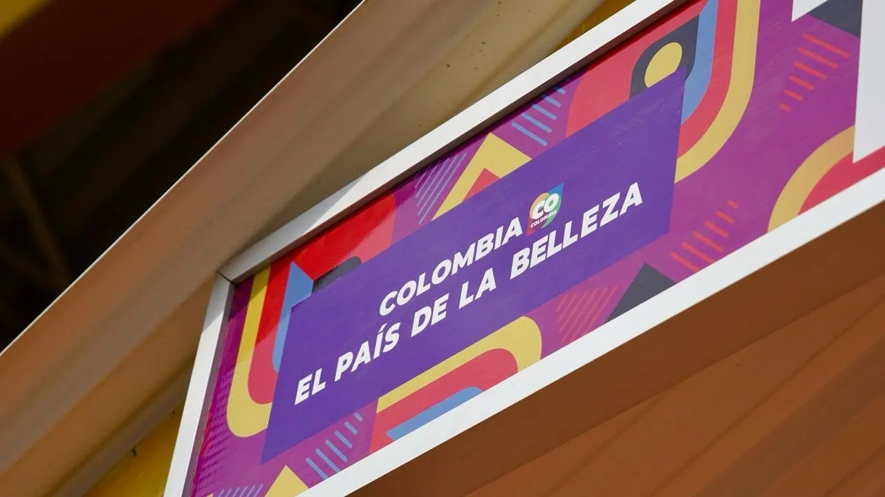 Pancarta con mensaje: "Colombia, el país de la belleza" en colores vibrantes y fondo decorativo.