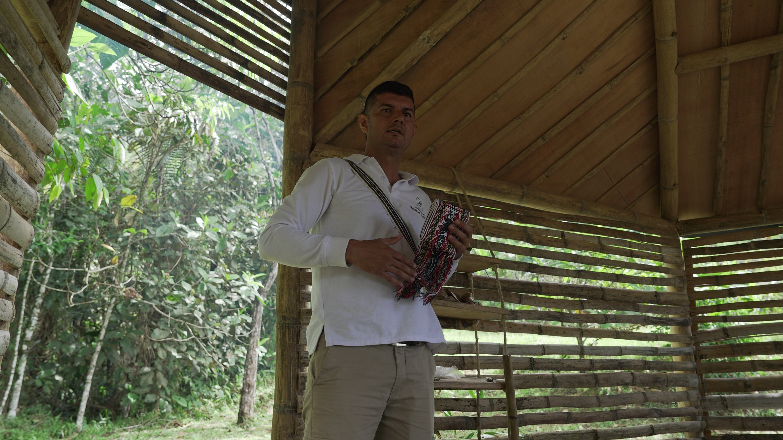 Hombre sosteniendo un textil en una estructura de madera en medio de la selva.