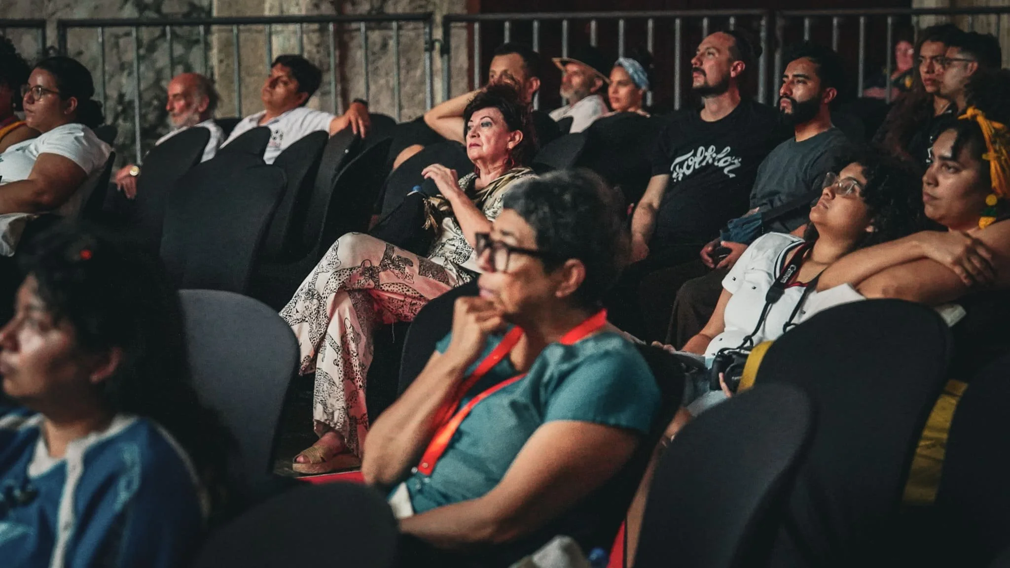Varias personas sentadas en un auditorio observando una presentación.