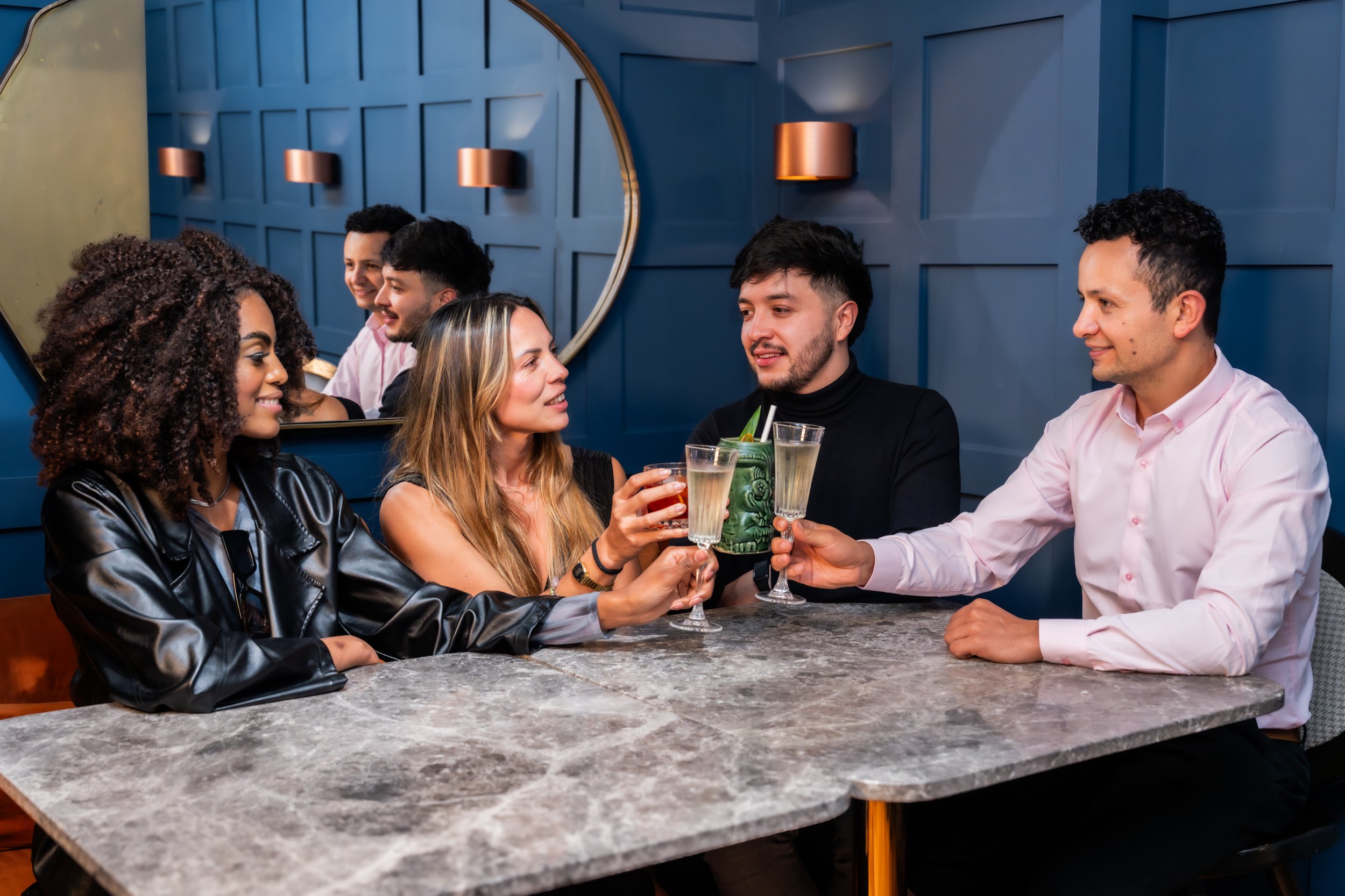 Grupo de seis personas en un bar, brindando con copas de champán.