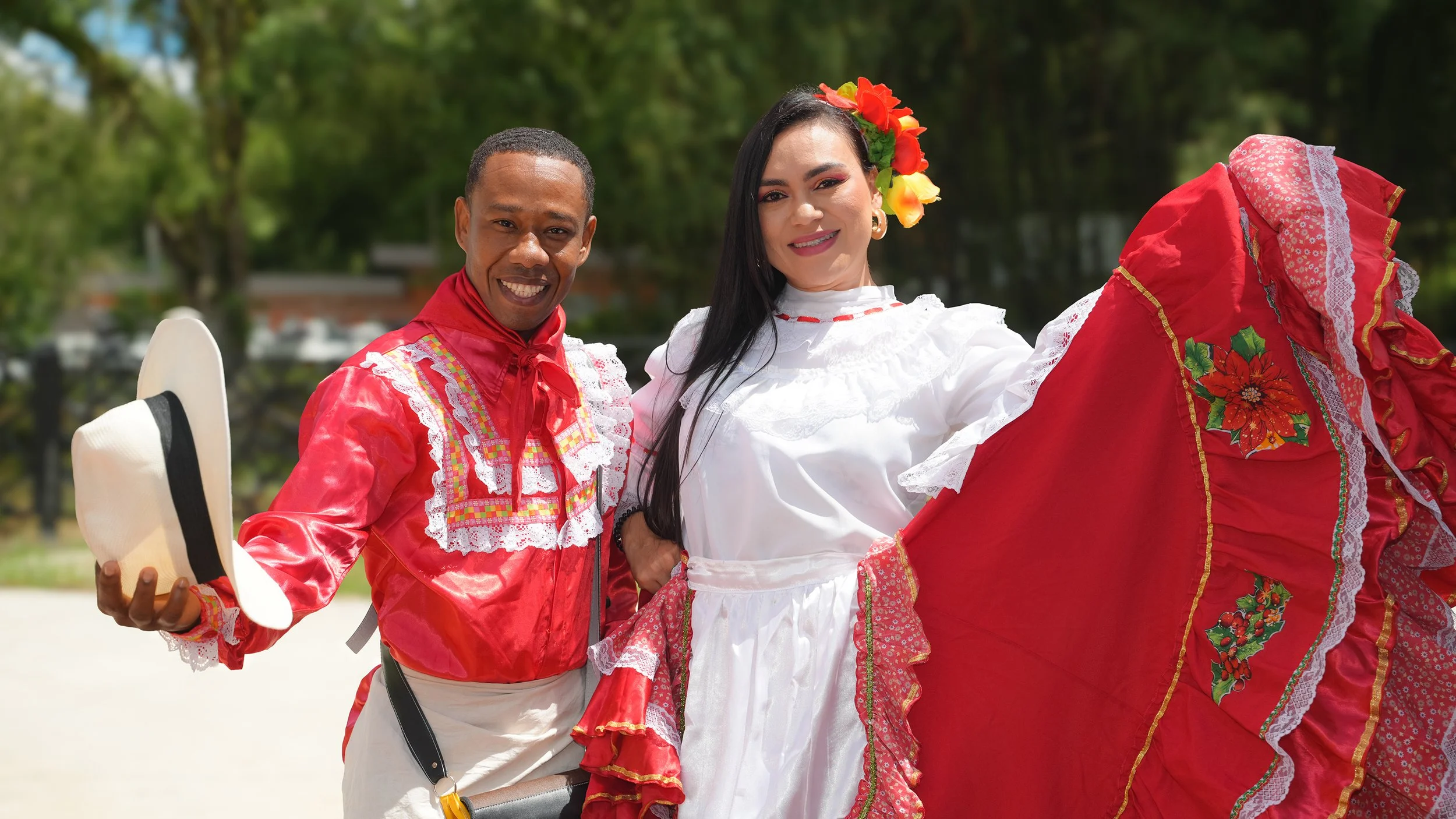 Grupo de personas en una ceremonia al aire libre con árboles de fondo, algunos llevan ropa tradicional colombiana y hay banderas de Colombia.