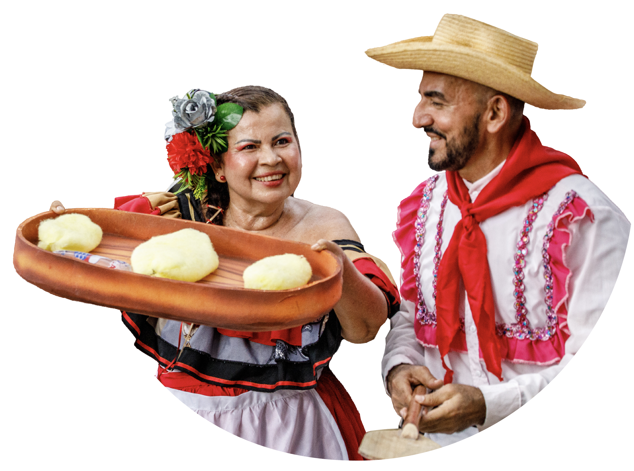 Personas con vestimenta tradicional mexicana intercambian un platón con lo que parecen ser alimentos tradicionales, celebrando con alegría y sonrisas.