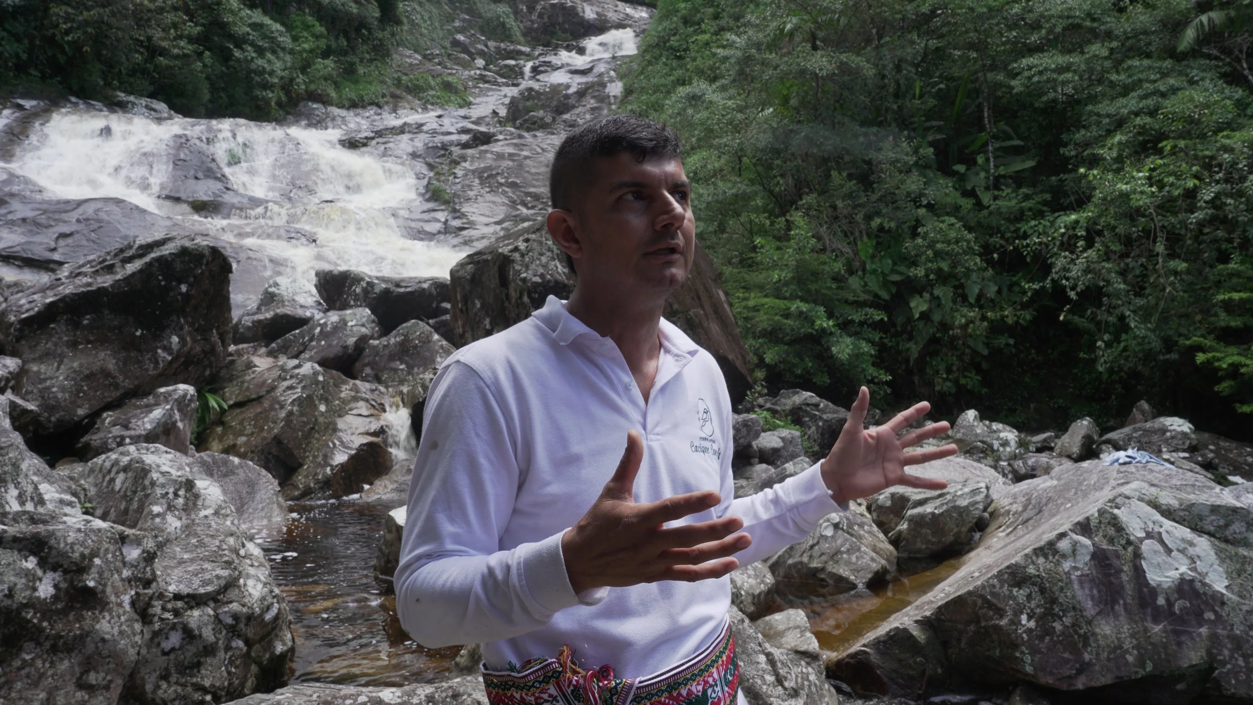 Un hombre hablando en un río rodeado de naturaleza.