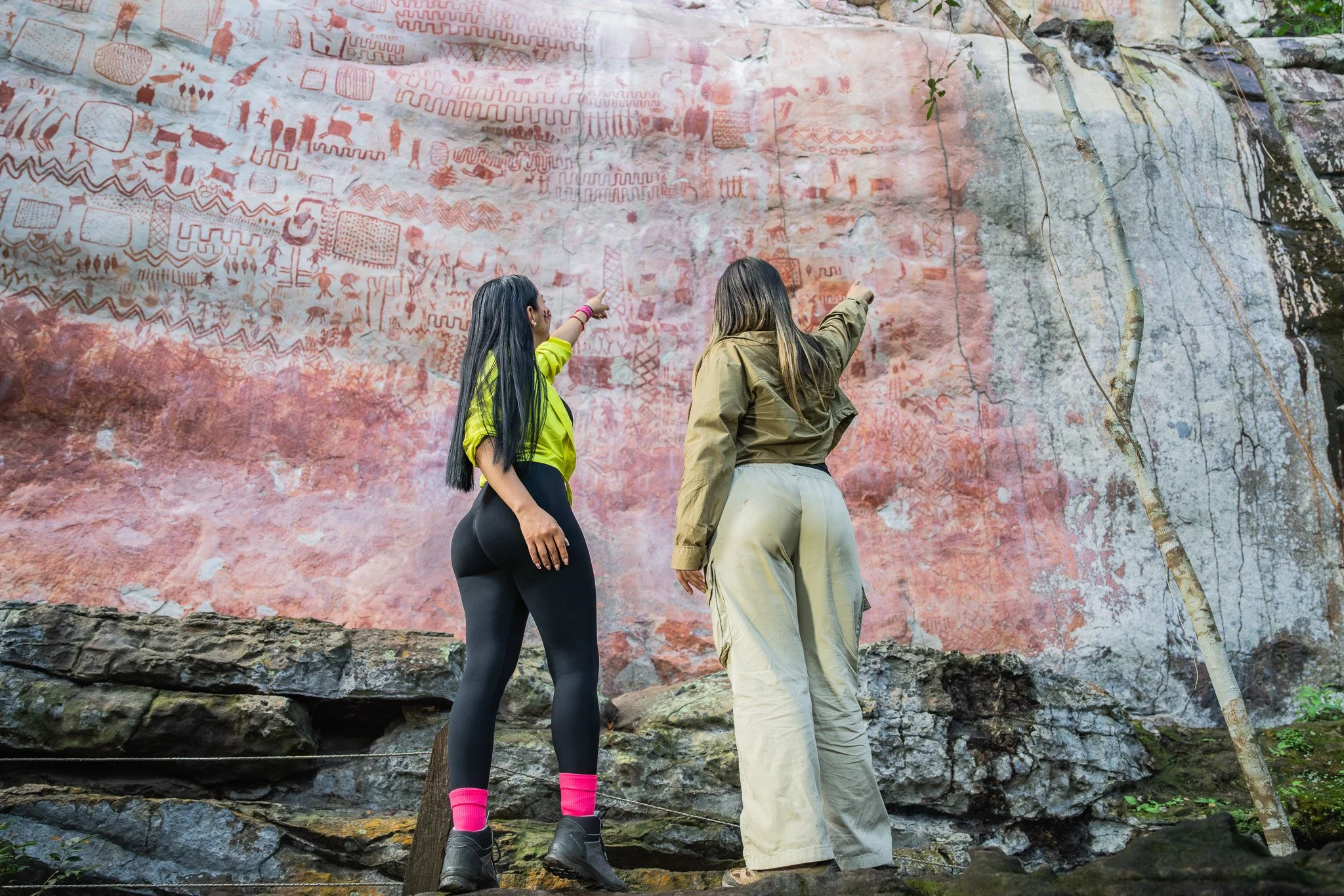 Dos mujeres observando petroglifos en una roca.