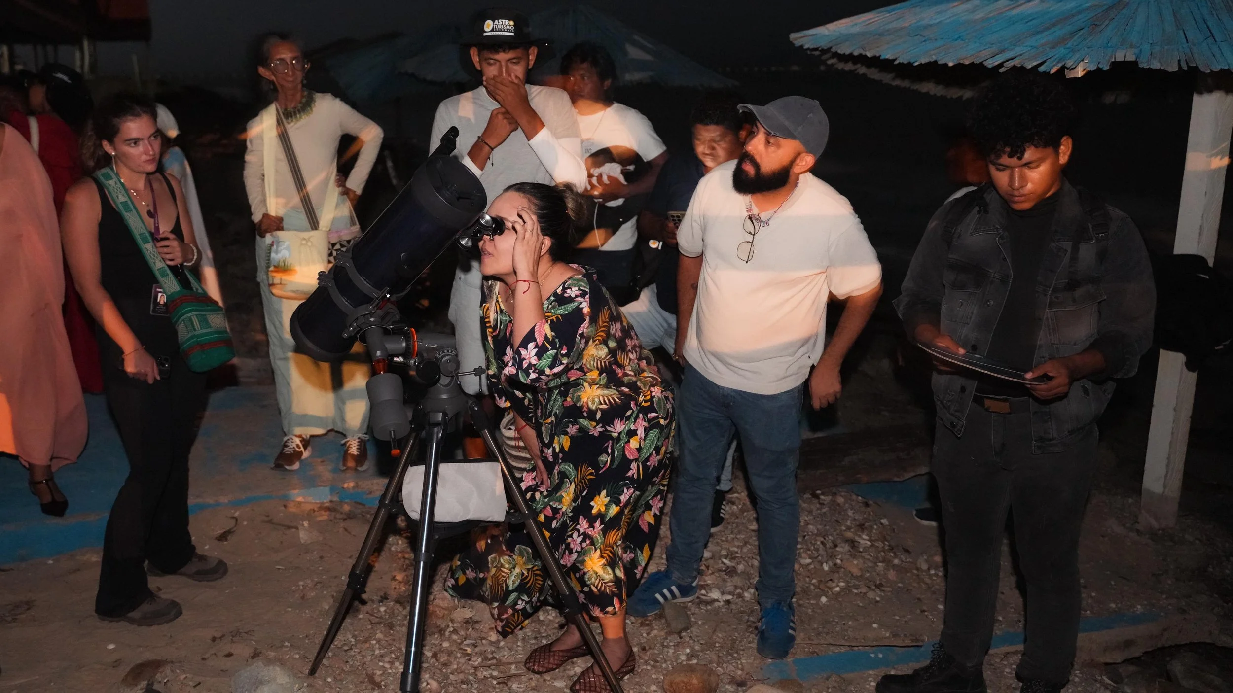 Grupo de personas observando un telescopio en exteriores de noche