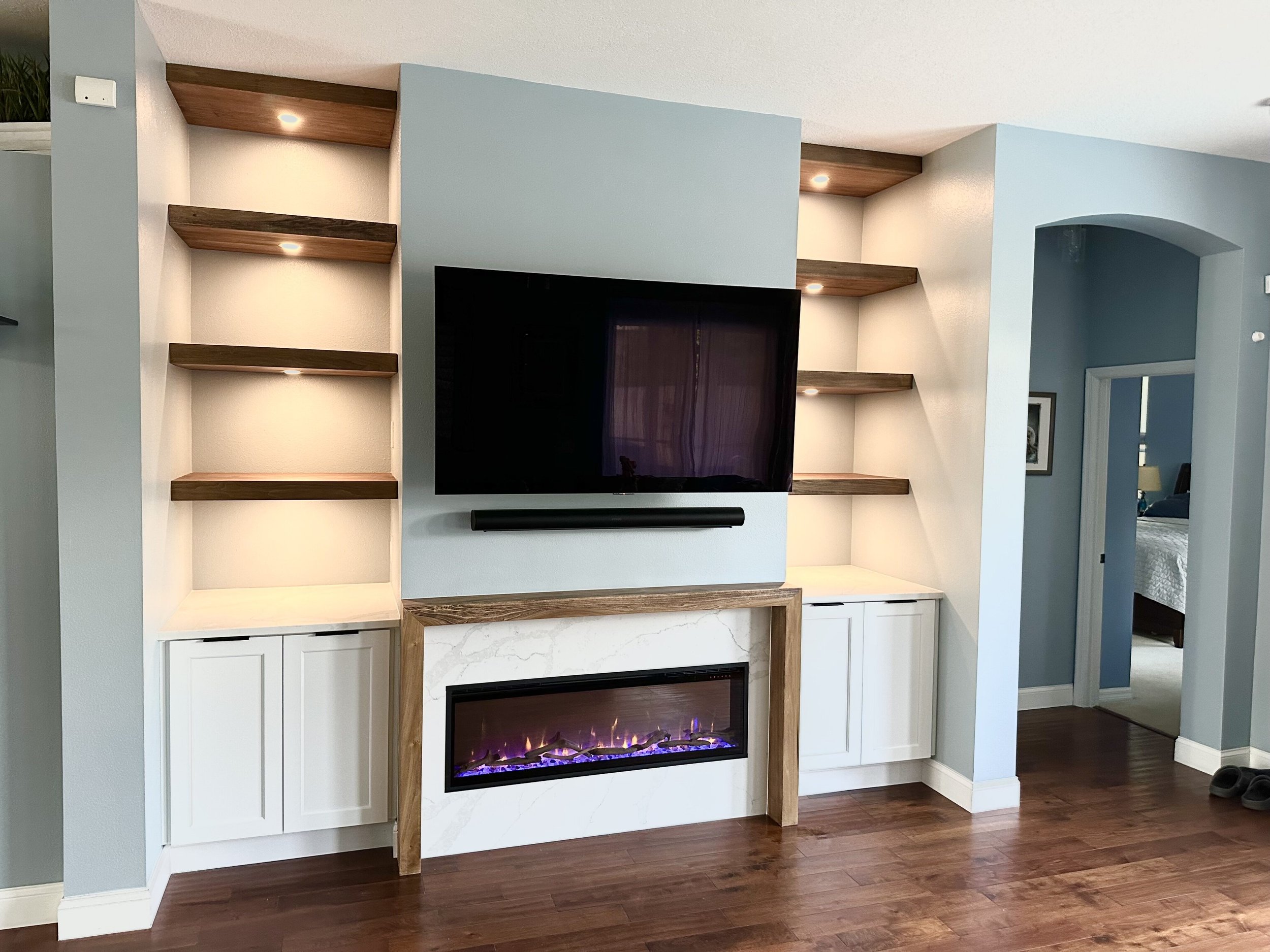 Custom built-in entertainment center in Montclair Apopka with poplar floating shelves, quartz fireplace surround, and integrated LED lighting.