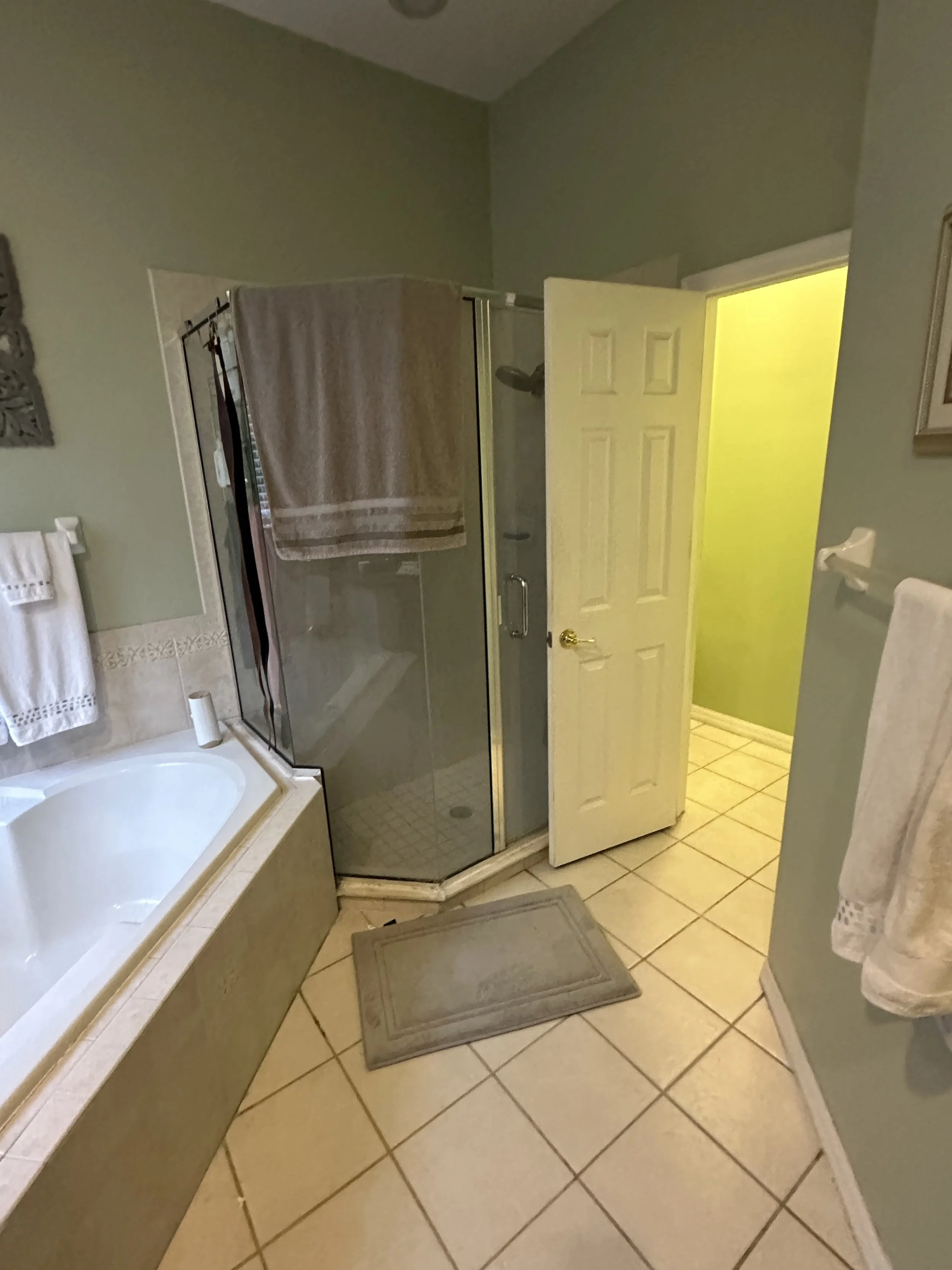 Original corner garden tub and neo-angle glass shower before the Lake Mary primary bathroom renovation.