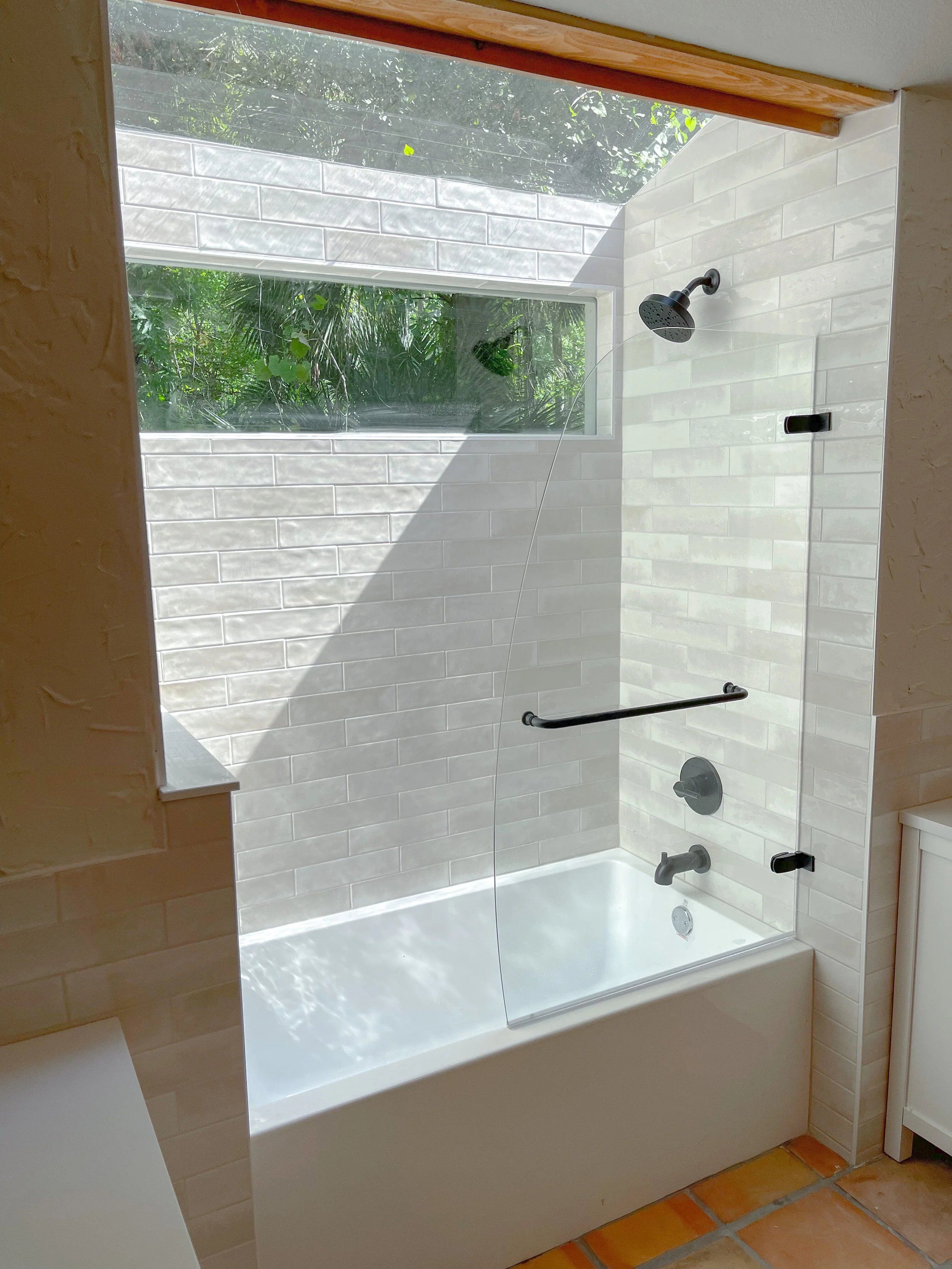 Bathroom remodel in Sabal Point Longwood with tub and shower combination, subway tile, black fixtures, and natural light window.