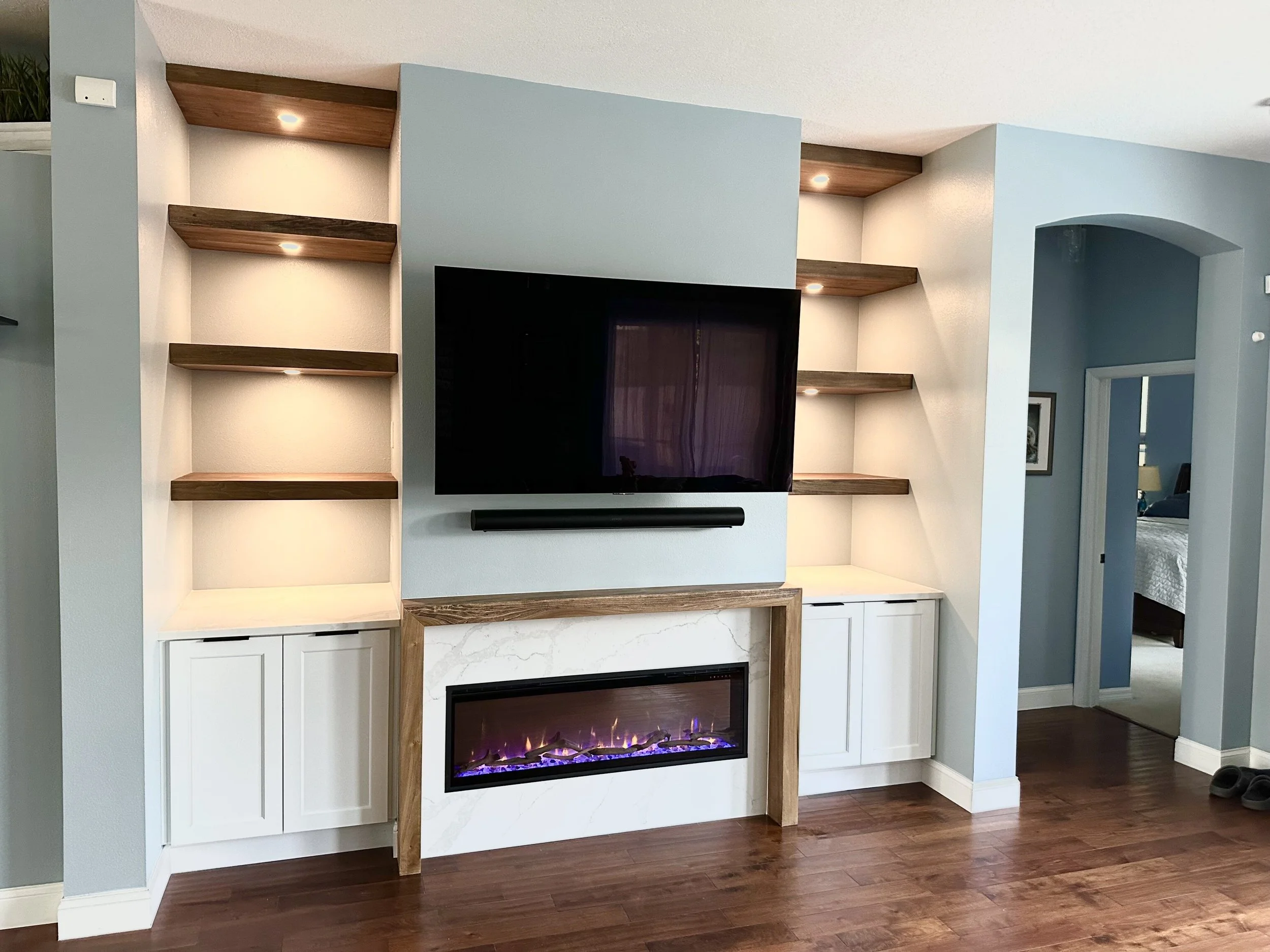 Custom built-in entertainment center in Montclair Apopka with poplar floating shelves, quartz fireplace surround, and integrated LED lighting.
