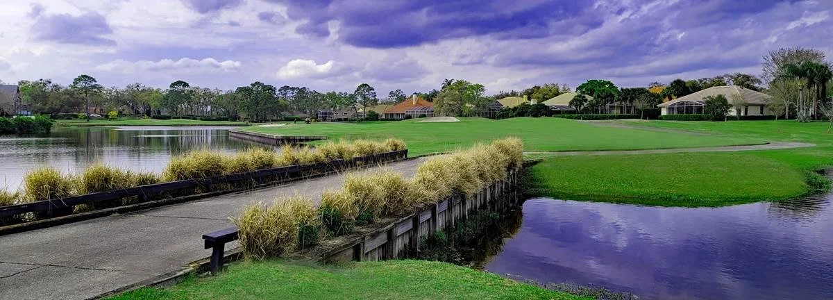 Manicured golf course fairway and green beside a pond in Heathrow, Florida.