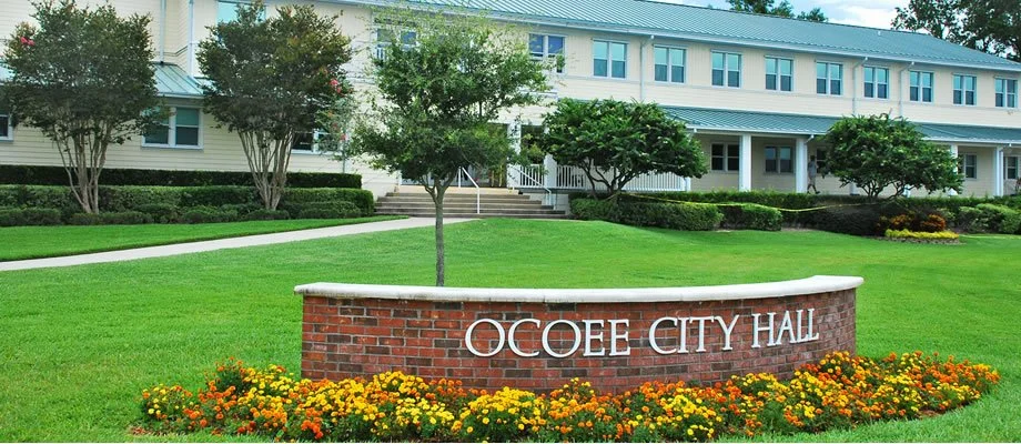 Ocoee City Hall sign in front of a well-maintained lawn and building with trees.